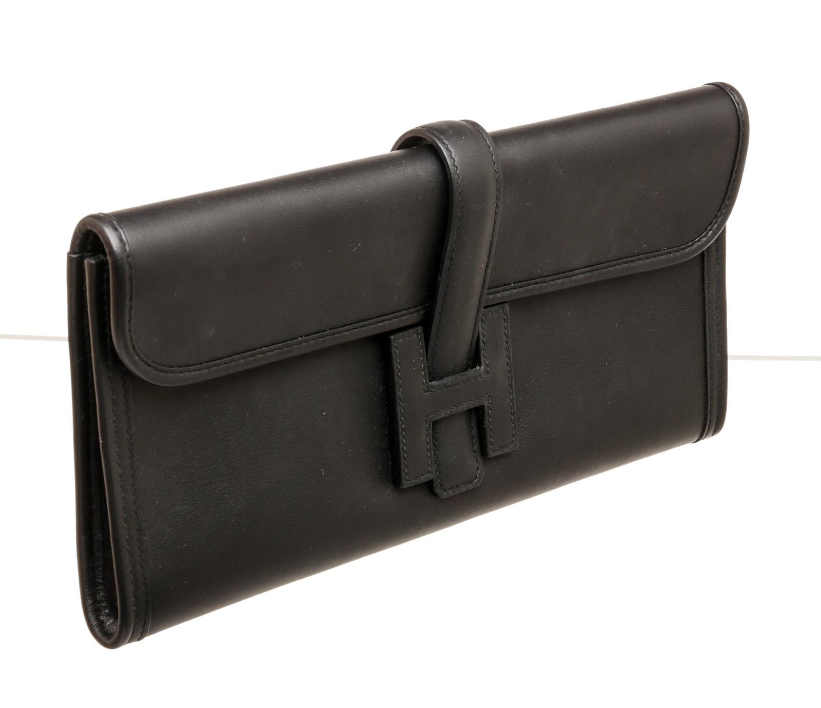 100% Authentic 

This stylish clutch is crafted of luxurious swift calfskin leather in black. It features a cross over flap with a strap that tucks under a leather Hermes 