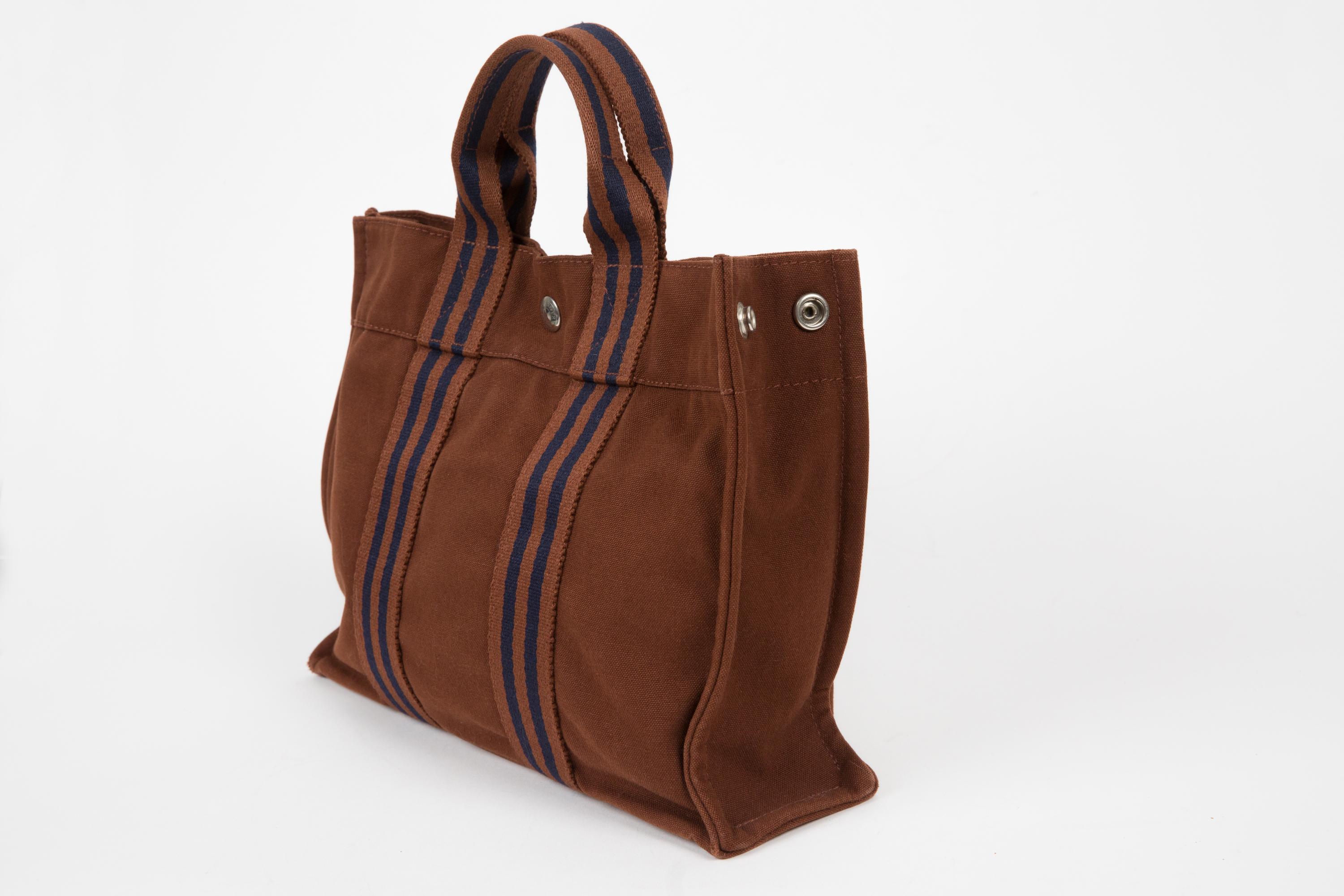 Hermes nut “Toto” PM tote bag featuring featuring navy stripy details, top handles, top logo snap opening, inside zipped pocket.
Circa 1990s 100%cotton
In good vintage condition . 
We guarantee you will receive this iconic item as described and