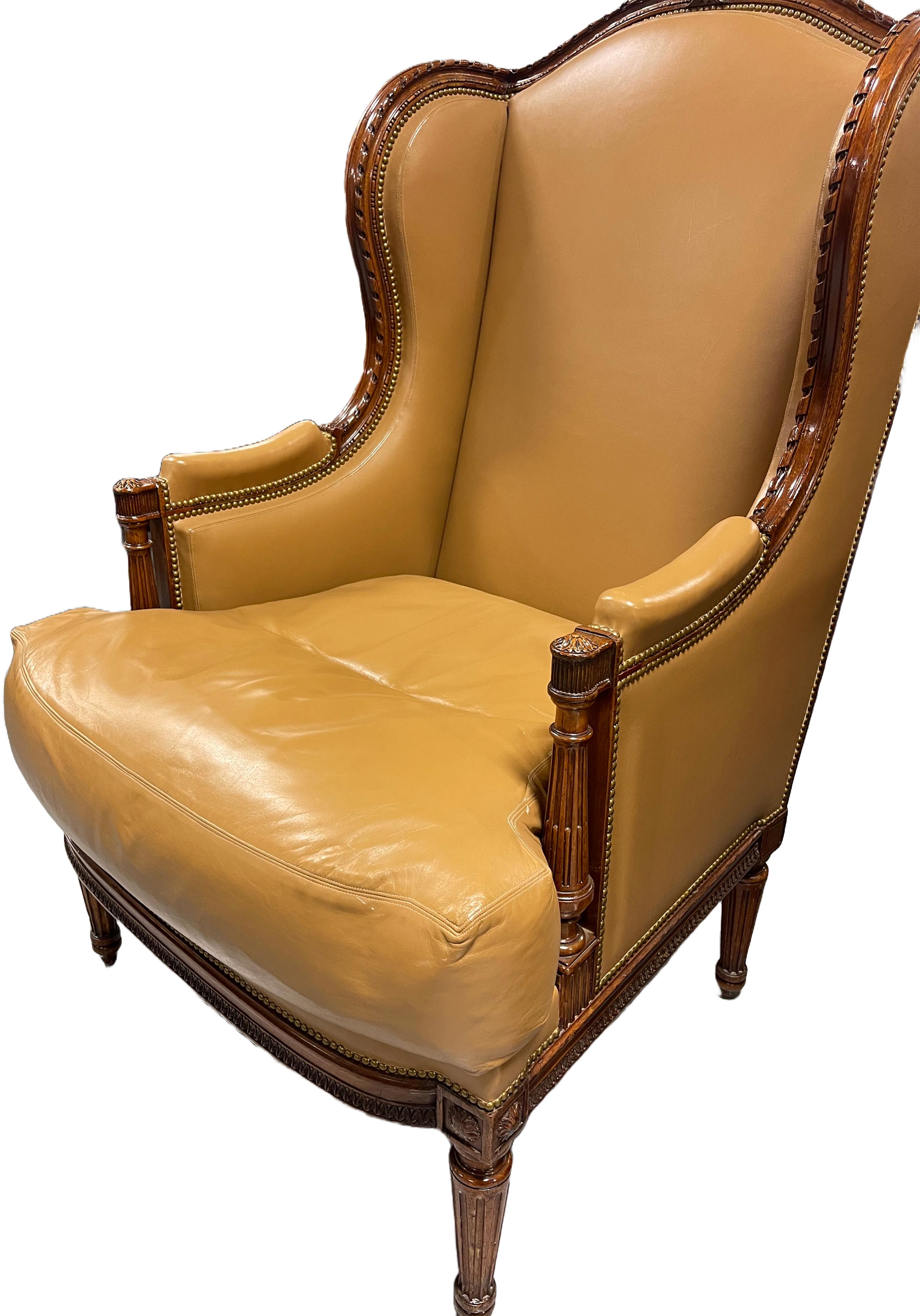 A handsome patinated Hermes ochre leather wing winged bergère. Bronze nail heads line the exterior and inset of the back of the chair. Turned and fluted wood legs. Arms have a leather armrest. Hermes ochre patinated leather upholstery. Louis XVI,