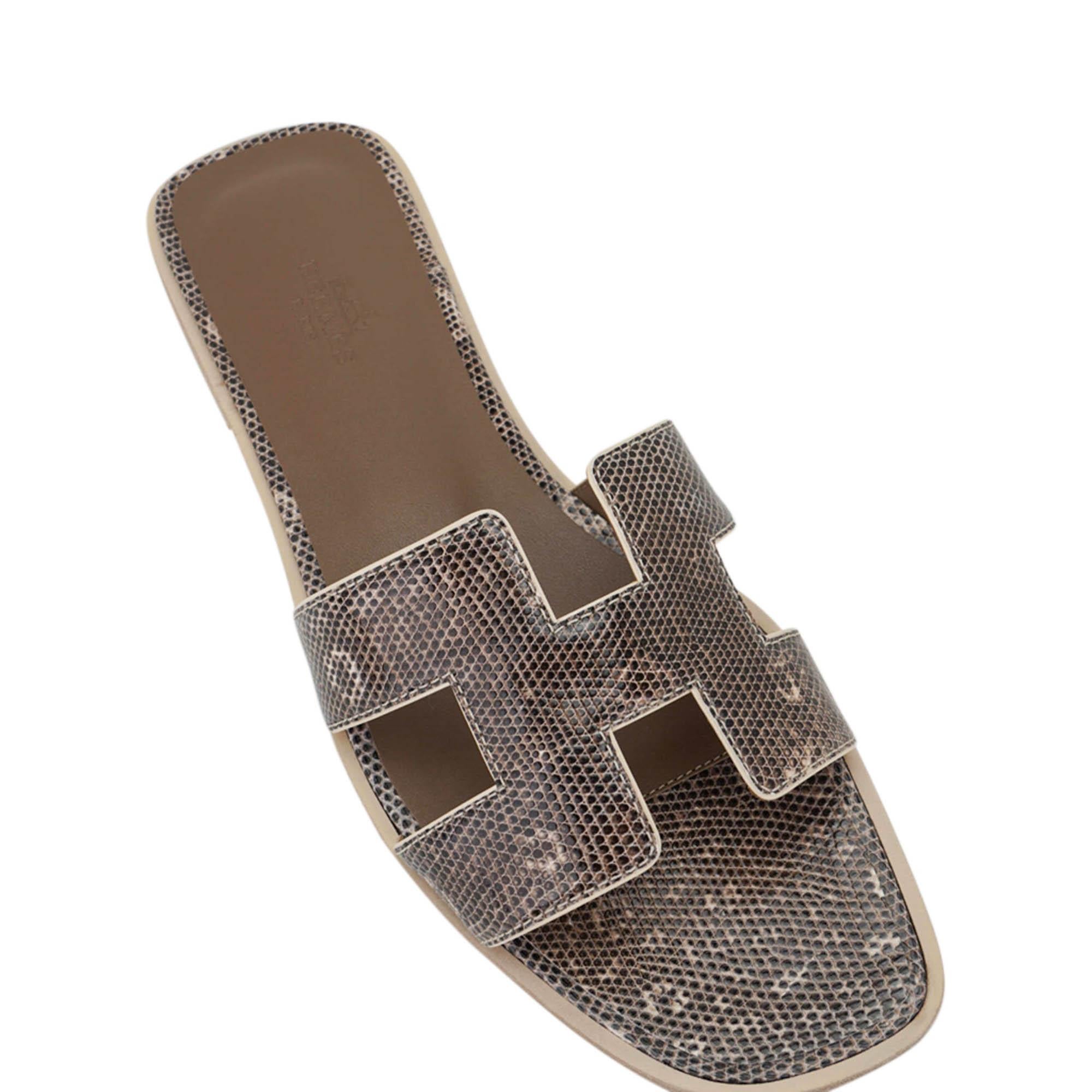 Mightychic offers a pair of Hermes Oran Ombre Lizard slides.
The iconic top stitched H cutout over the top of the foot in coveted Ombre lizard skin.
Etoupe embossed calfskin insole.
Wood heel with leather sole.
Comes with sleepers and signature