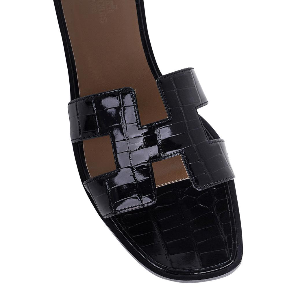 Mightychic propose des sandales Hermes Oran en alligator noir.
L'emblématique découpe en H sur le dessus du pied.
Classique et intemporel. 
Talon en bois et semelle en cuir. 
Livré avec des dormeurs, une boîte Hermès et un ruban. 
NEUF ou JAMAIS