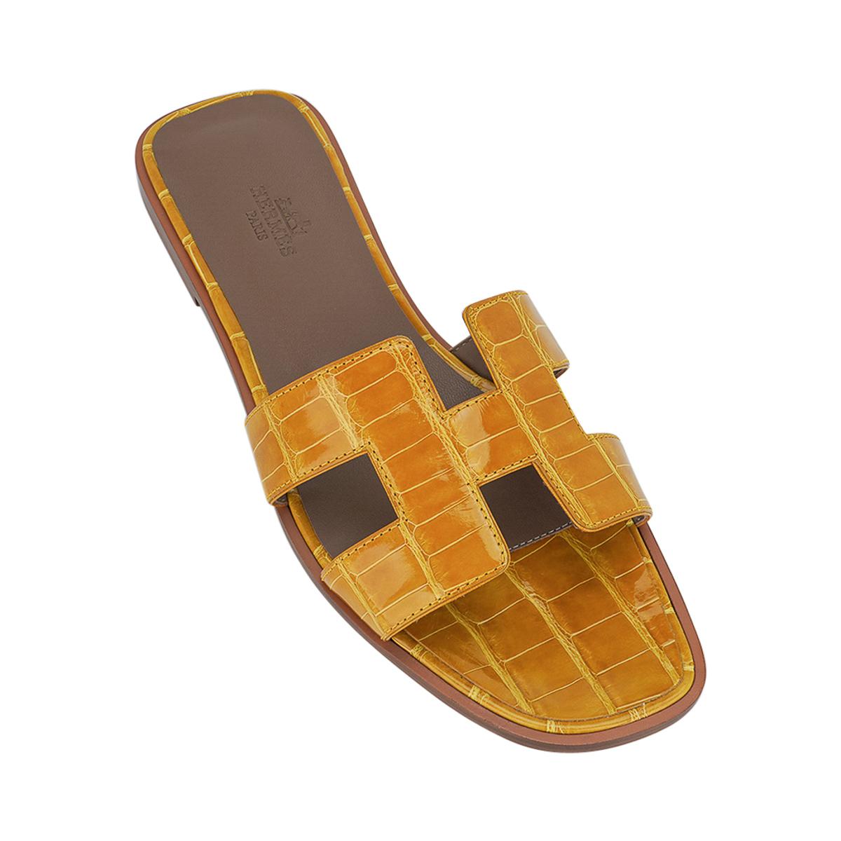 Mightychic offers Hermes Oran sandals featured in Jaune Ambre Alligator.
This stunning limited edition Hermes Oran flat slide sandal is a warm honeyed yellow.
The iconic H cutout over the top of the foot.
Embossed calfskin insole.
Wood heel with