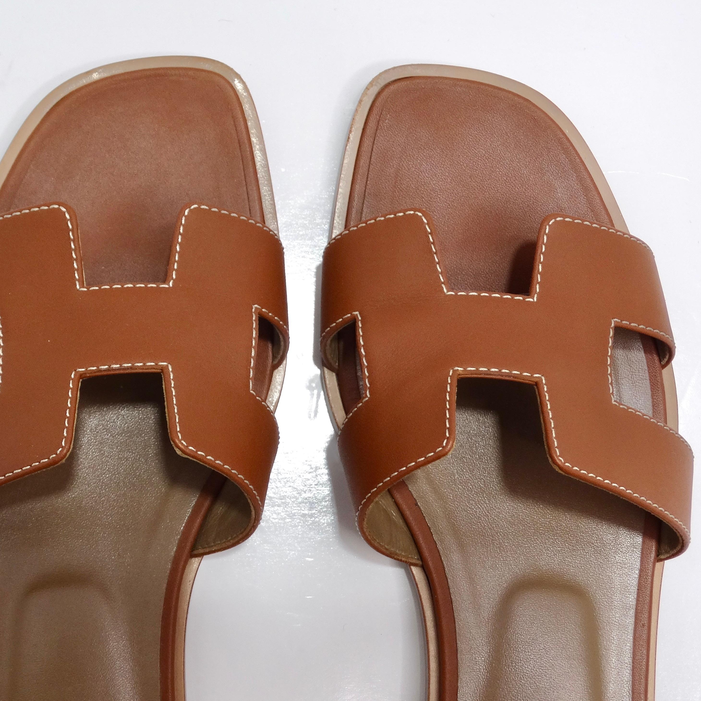 Introducing the epitome of understated luxury: the Hermes Oran Sandals in classic brown. Crafted from sumptuous camel brown leather, these slip-on sandals boast the iconic 