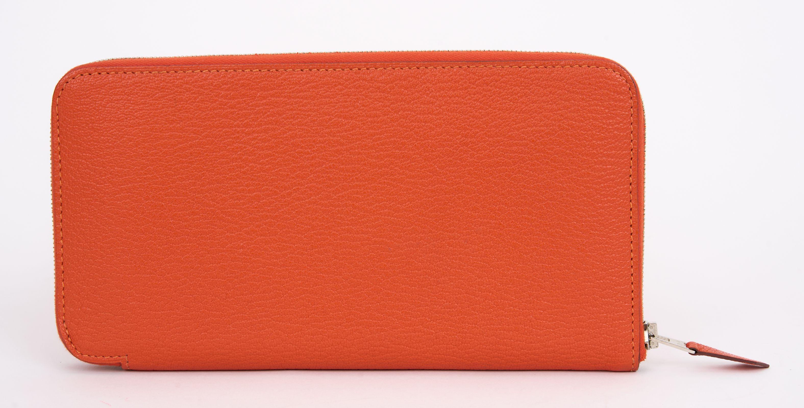 This Hermès Azap Classic Wallet is in Orange Epsom Leather with palladium hardware. The wallet features leather lining, two interior pockets with card slots, and an exposed zip closure. Comes with the original box.