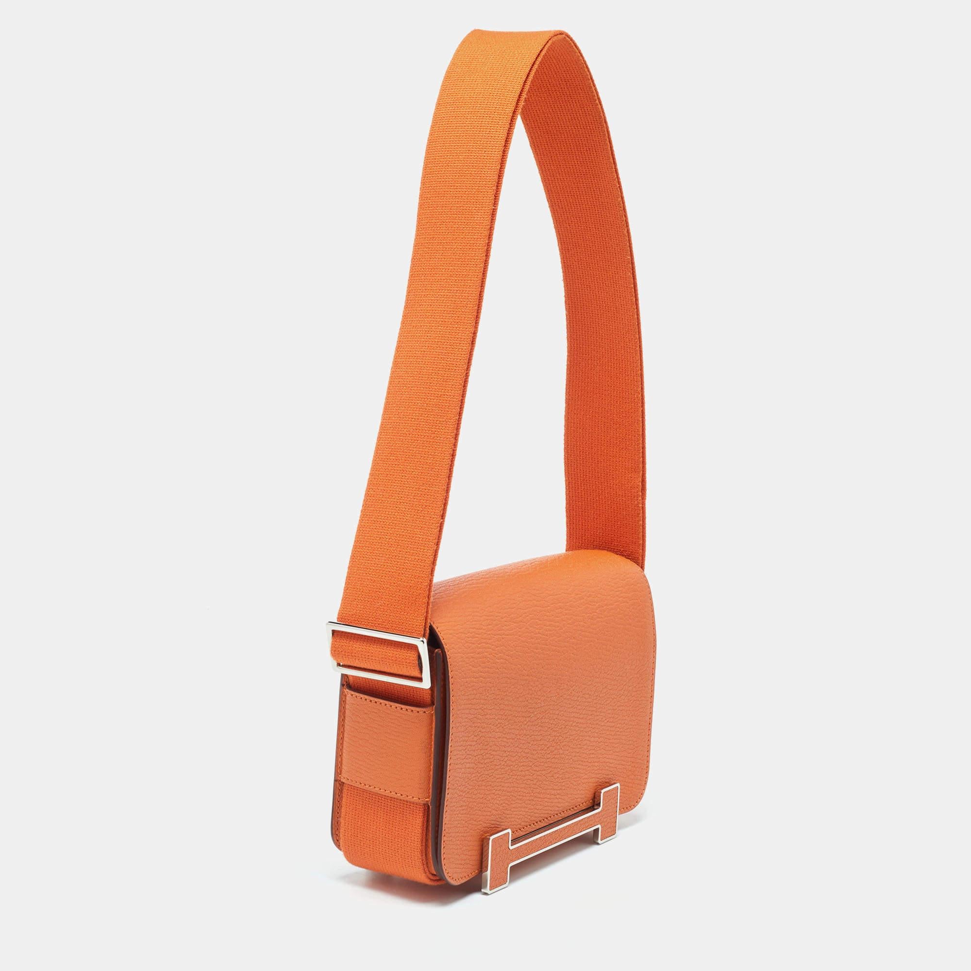 The Hermès bag is a luxurious fashion accessory. Crafted from vibrant orange Chèvre Mysore leather, it exudes elegance. The palladium-finished hardware adds a touch of sophistication. Its versatile design features a sangle strap for easy carrying,