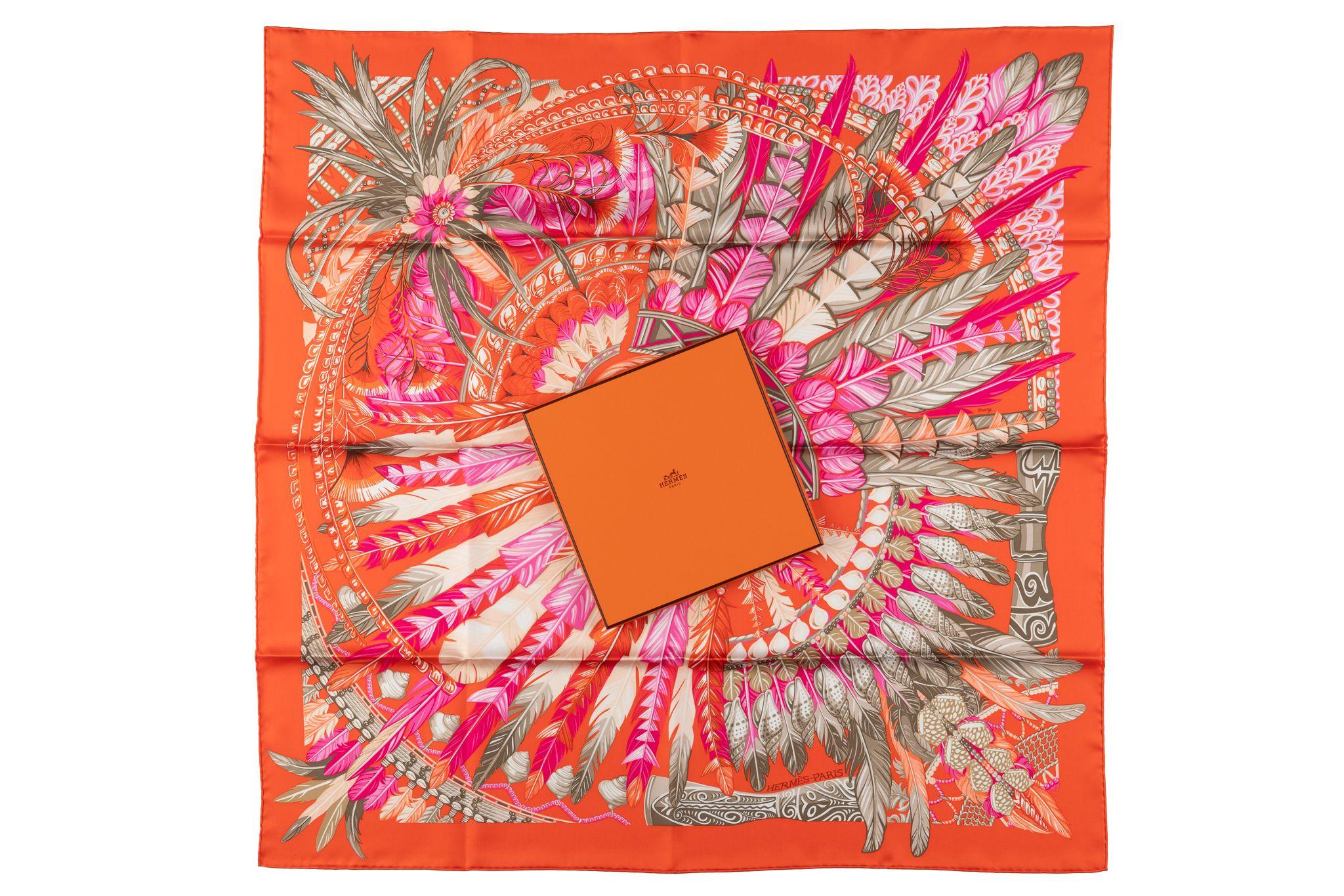 The Hermès “Orange Dance Pacifique“ scarf silk scarf by Laurence Bourthoumieux, pays tribute to the culture of New Guinea. The scarf features the feather and cowry adorned headdresses of the Pacific in orange and rose colorway. Comes with an