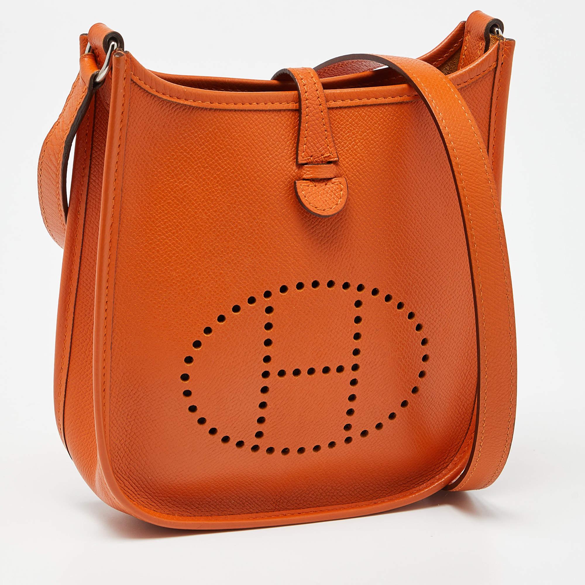 The Hermès Evelyne TPM Bag is a small, crossbody bag known for its vibrant orange color and durable Epsom leather construction. It features a perforated 