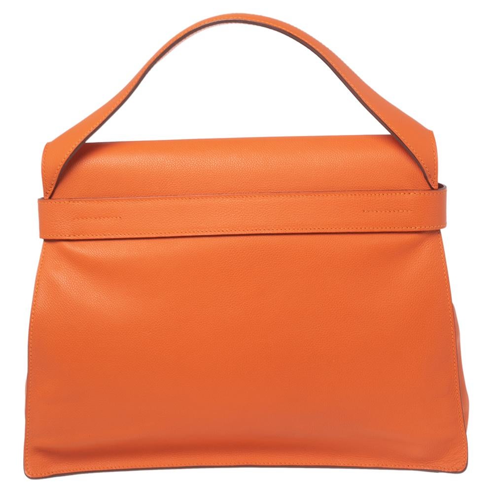 This Hermes bag is anything but ordinary! It has been crafted from Evercolor leather and creatively styled with an adjustable buckle belt closure on the front. It boasts of a single top handle and a leather-lined interior that gladly embraces all