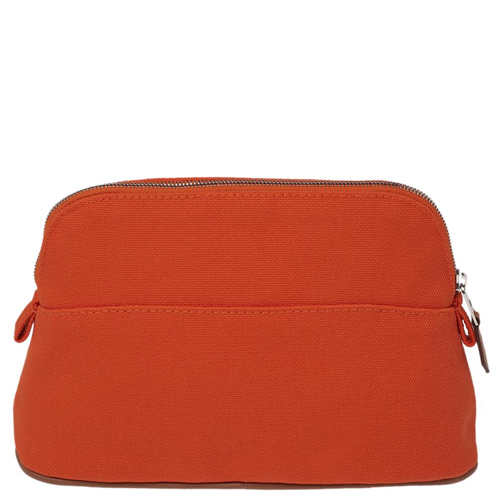 This Bolide travel case from Hermes is made from orange canvas that will last you for years to come. This sleek design slips easily into your handbags. It is finished with a top zipper, the brand label at the front, and a sturdy base with leather