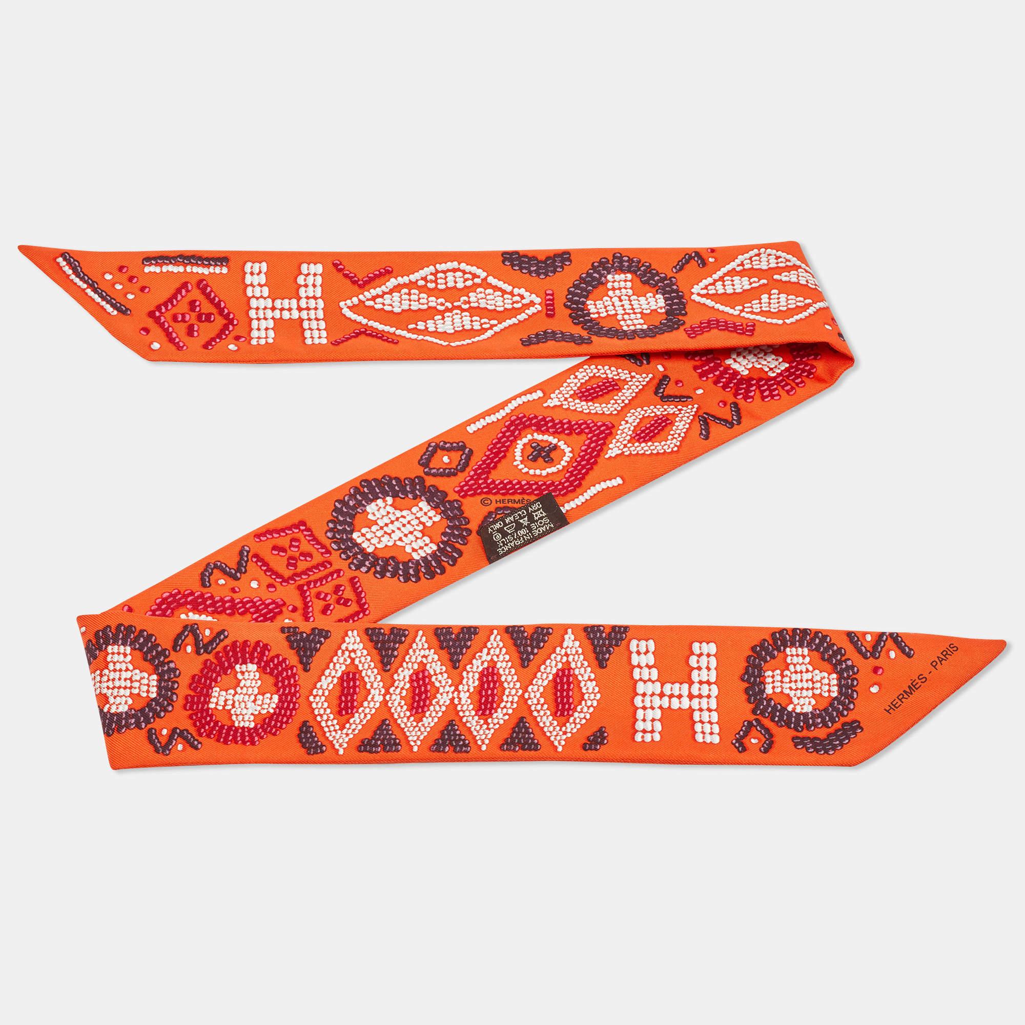 The Hermès twilly is a luxurious accessory featuring a vibrant orange hue and the iconic Kelly En Perles print. Crafted from high-quality silk, it adds a touch of elegance and sophistication to any ensemble.

