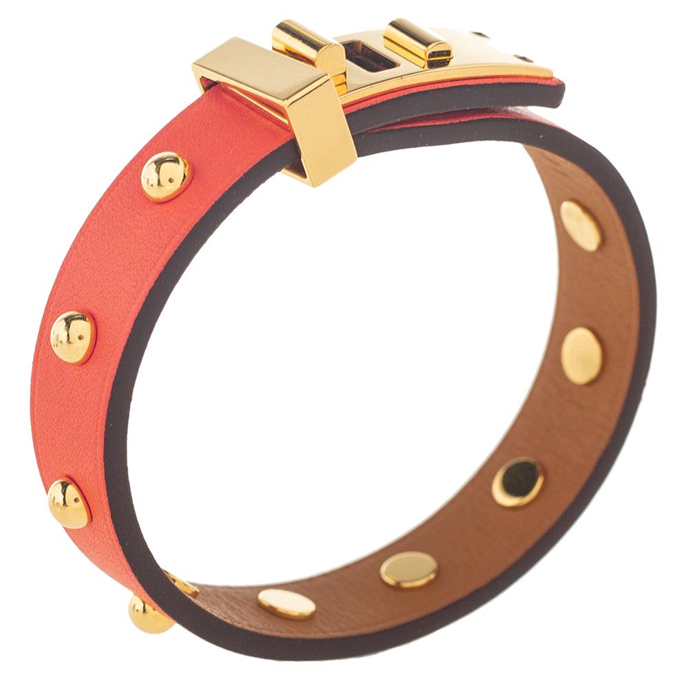 This Hermès bracelet is a chic accessory that can be paired with everything, from casuals to evening outfits. Made from leather, it is beautified with a gold-plated metal lock at the front and stud all over. The orange bracelet wraps around your