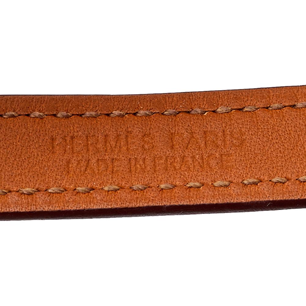 This Hermès Double Tour bracelet is a chic accessory that can be paired with everything, from casuals to evening outfits. Made from leather, it is beautified with pyramid studs and a ring in palladium-plated metal. The orange bracelet has a long