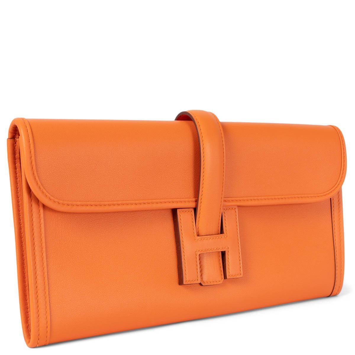 100% authentic Hermès Jige Elan 29 clutch in orange Veau Swift leather. Features a flap with strap that tucks under a leather Hermès 