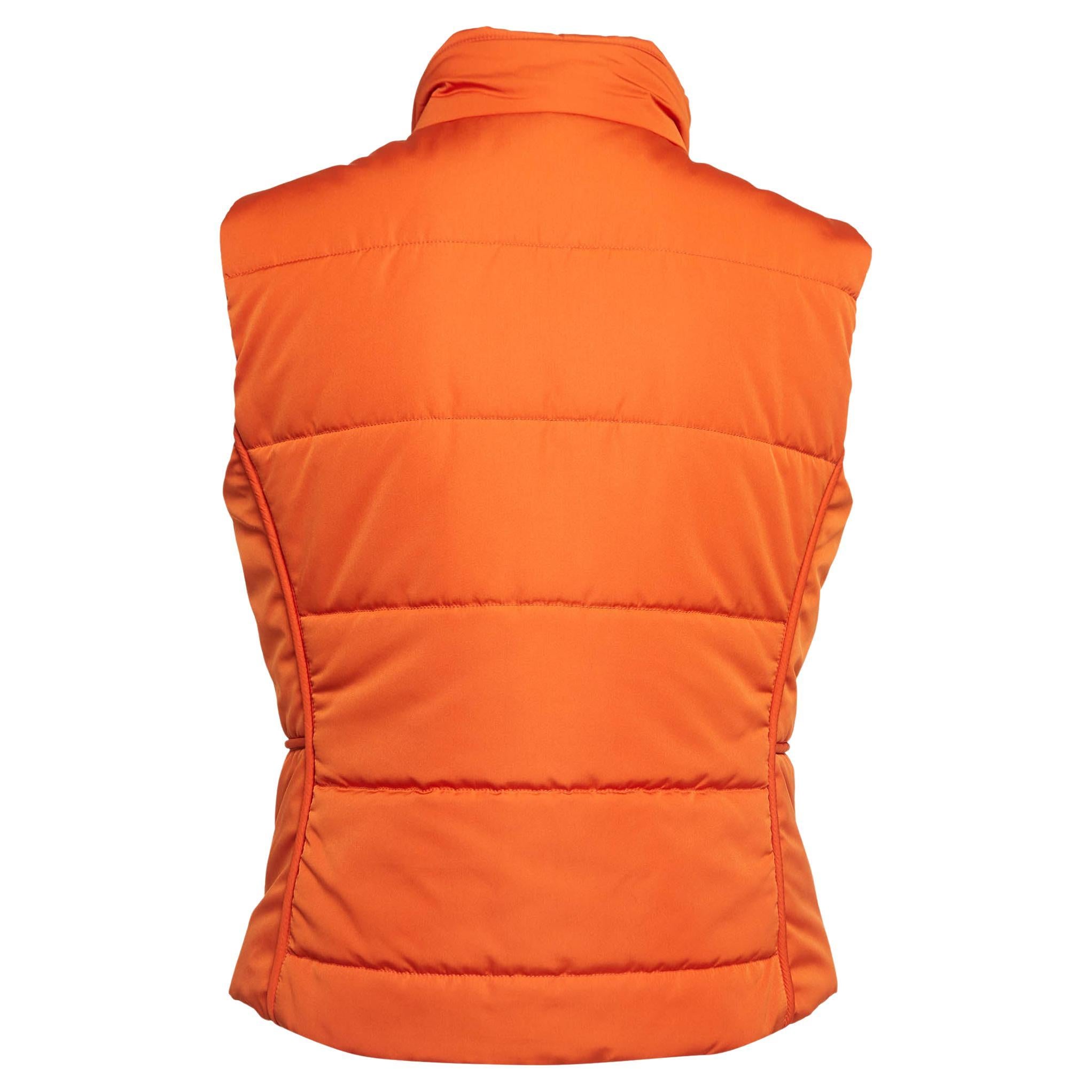 Wrap yourself in the refined luxury of the Hermès vest. Crafted with precision and finesse, this vest boasts a sleek silhouette and quilted design. Its vibrant orange hue adds a pop of color to any ensemble, while the sleeveless cut offers