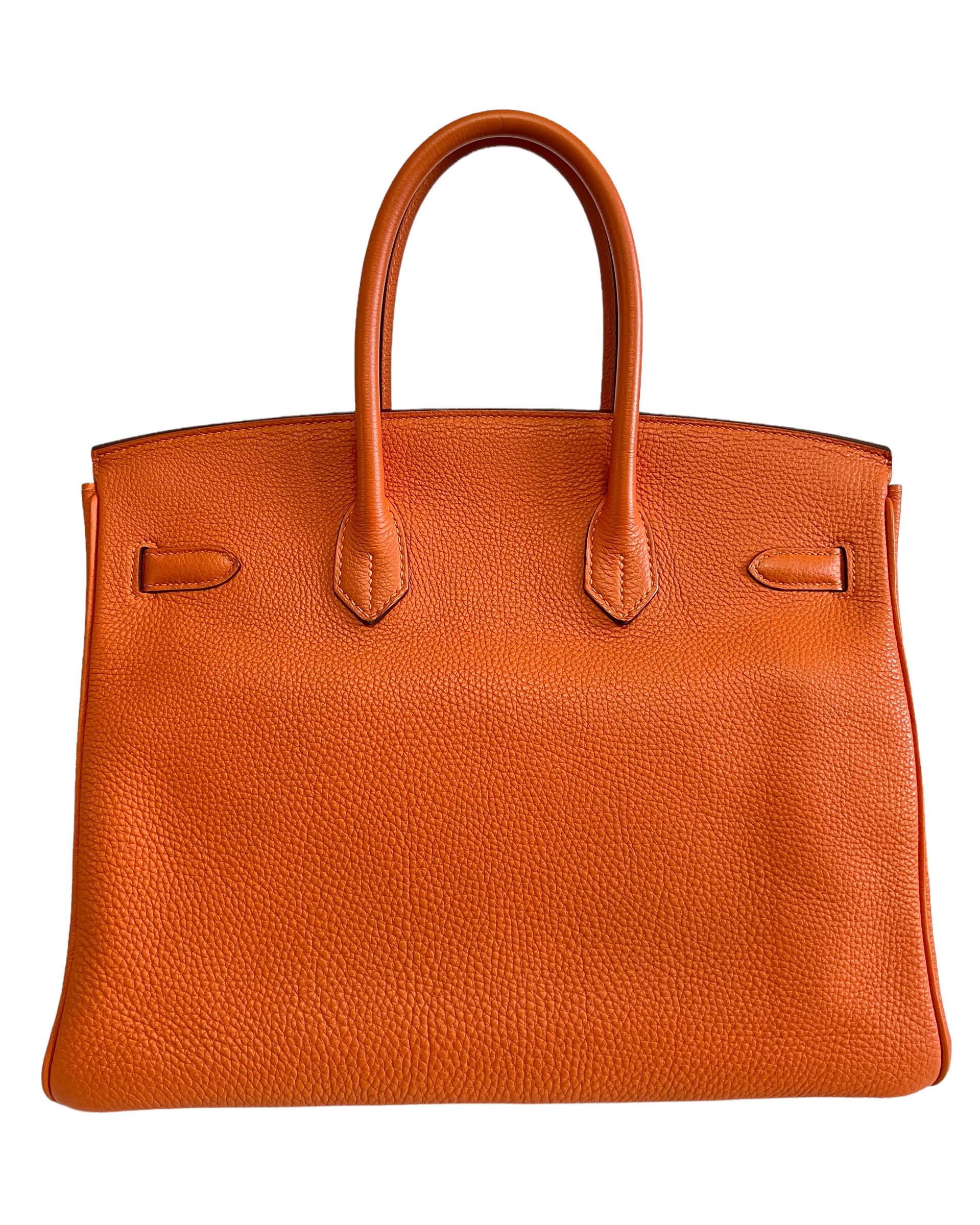 This authentic Hermès Orange Togo 35 cm Birkin is in pristine unworn condition with the protective plastic intact on the hardware.  Waitlists exceeding a year are commonplace for the intensely coveted classic leather Birkin bag.  Each piece is hand