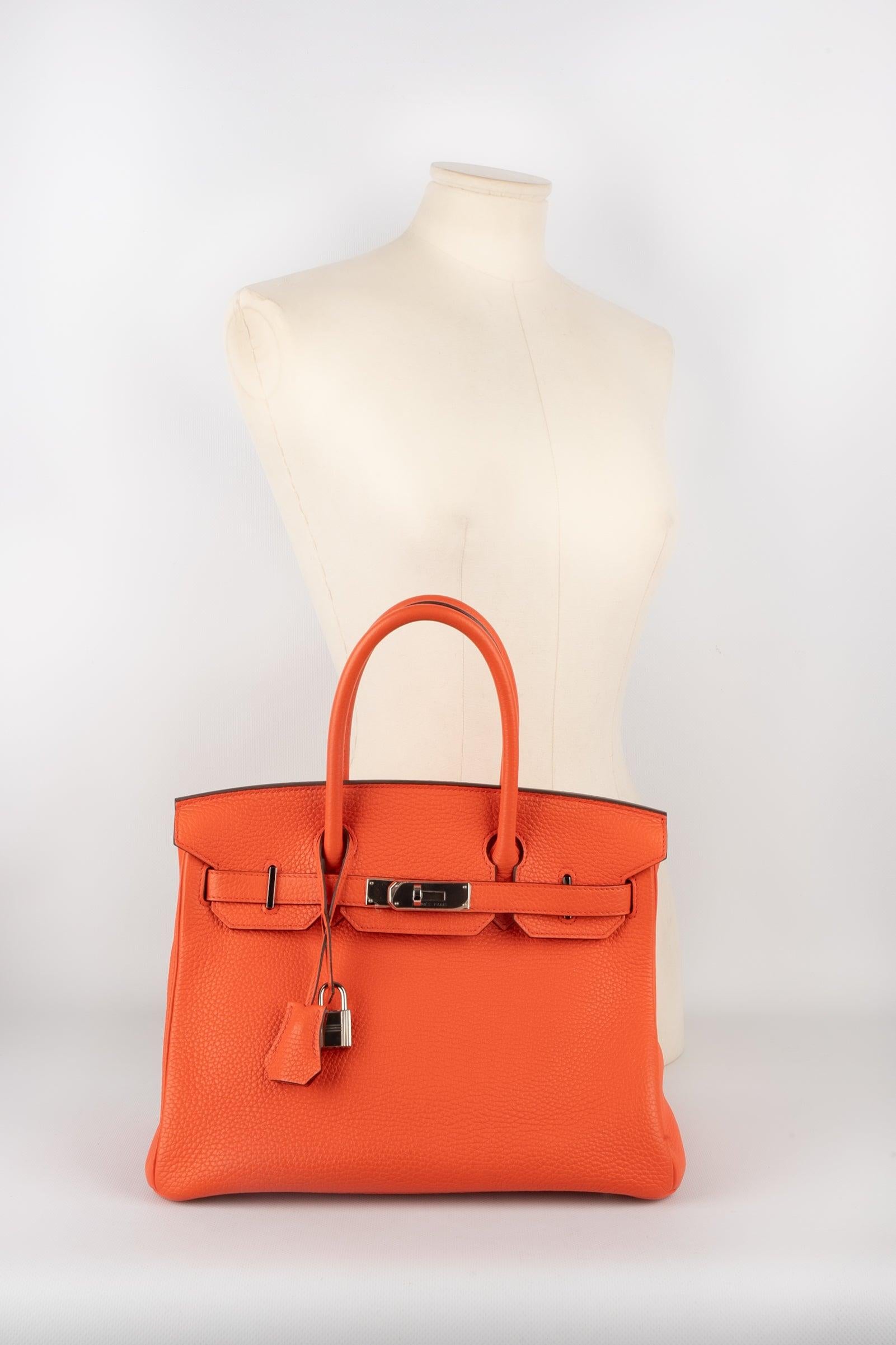Hermes - (Made in France) 30 cm poppy orange togo calf leather Birkin bag with palladium-plated silvery metal ties and fastener, with a double handle, keys under a tiny cloche, and a padlock. 2016 collection piece sold with a certificated of