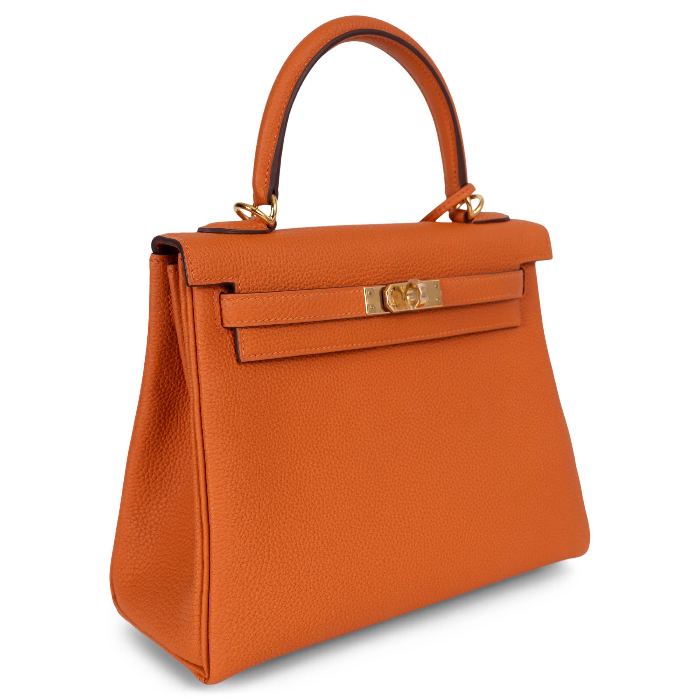 Diese 100% authentische Hermès Kelly 25 Retourne Tasche ist aus geschmeidigem orangefarbenem Veau Togo Leder gefertigt und mit eleganten vergoldeten Beschlägen versehen. Die weiche Retourne-Konstruktion verleiht ihm eine leicht entspannte