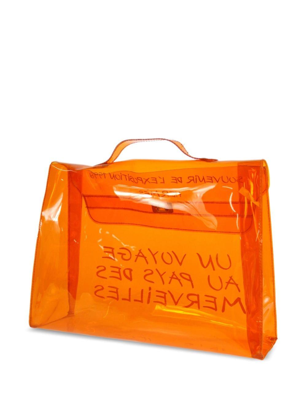 Sac de plage Kelly 40 en vinyle orange Hermes 1998, en forme de sac en plastique transparent, avec des accessoires en métal argenté doré, un slogan imprimé sur le devant, une fermeture à rabat, une anse simple en vinyle transparent permettant de