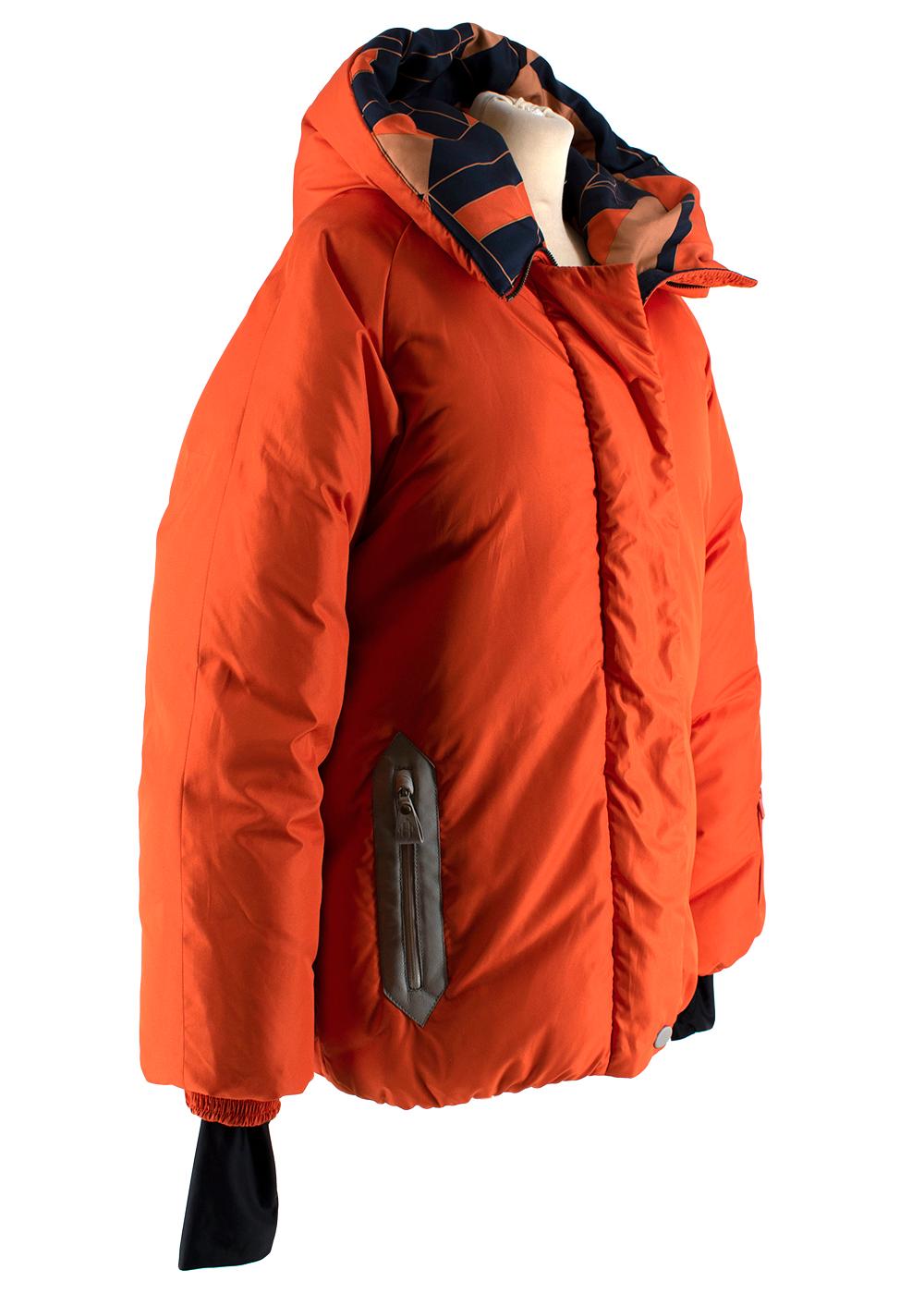 Hermes Oversize Hooded Orange Puffer Coat with Scarf Print Lining 40

- Patterned Lining 
- Oversized Hood 
- Grey Veau-Calfskin Leather Zip Trim
- Centre Full Length Zip and Button Fastening 
- Small Sleeve Zip Pocket 
- One Interior Pocket