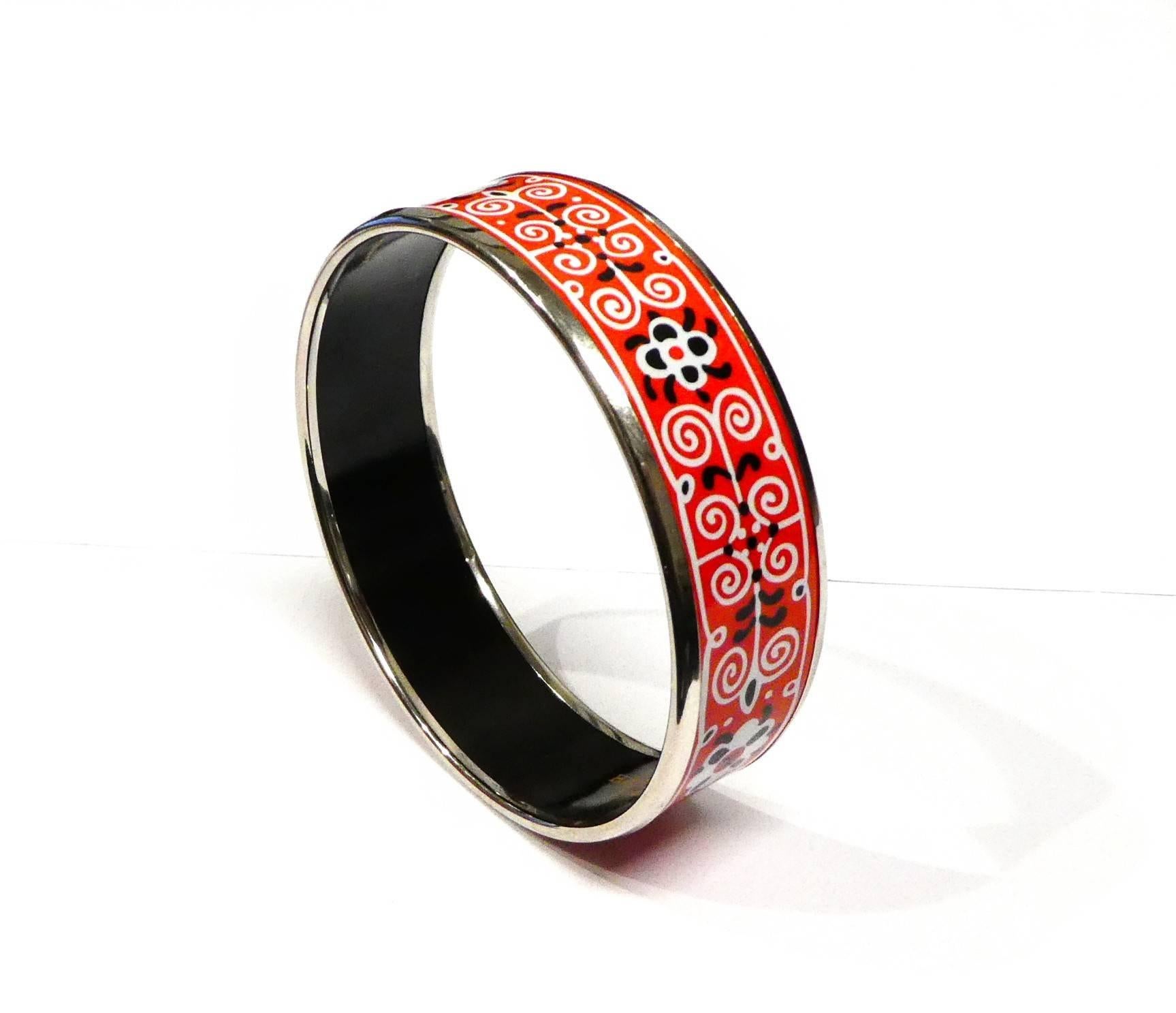 For sale we have a Hermes Bagle Bracelet with a red, black, and white floral motif design. This bracelet is Palladium-Plated with the design in Enamel. We estimate this piece fits a 6 inch wrist and may feel tight because of it's thickness of