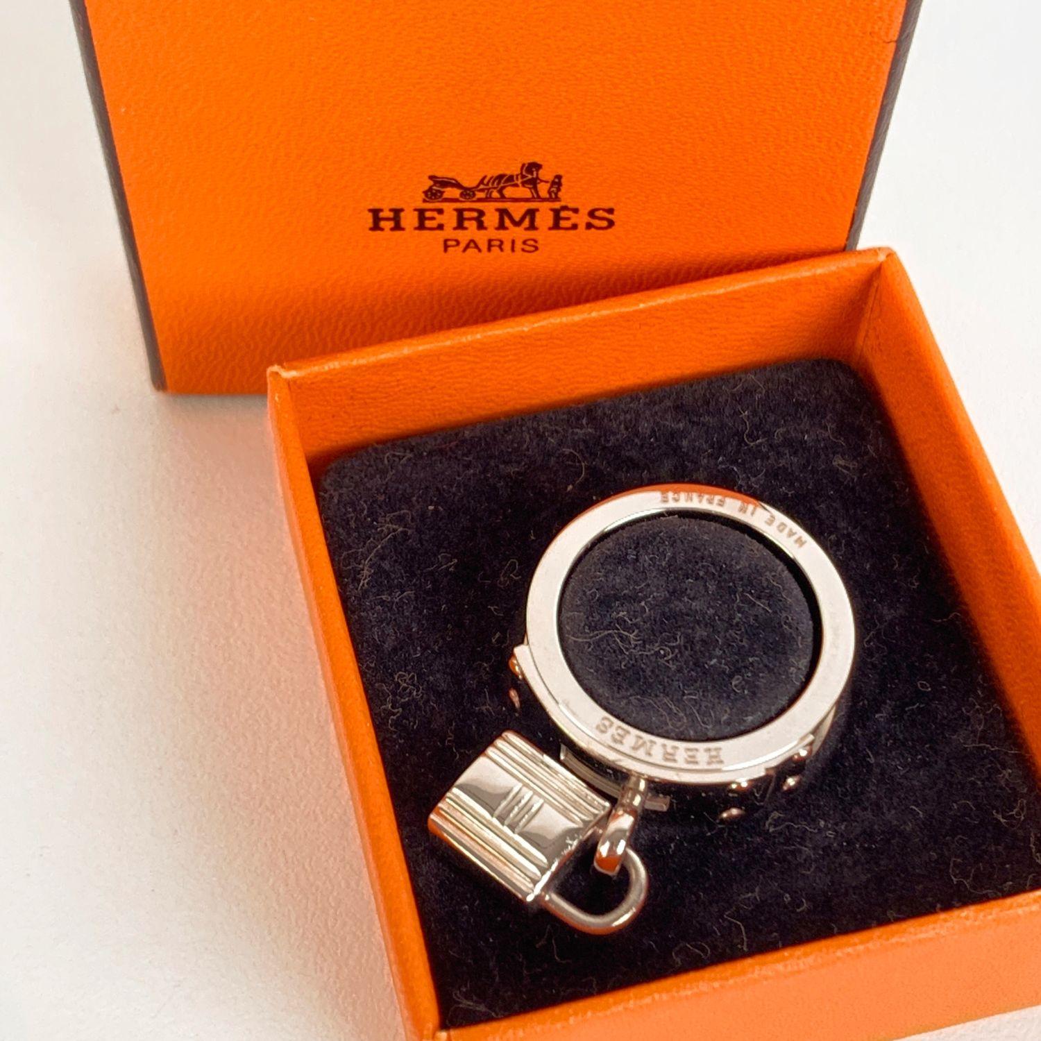 HERMES silver metal Palladium Swift Kelly Lock scarf ring with black leather insert. It features the iconic signature Kelly closure with its palladium padlock dangling on the front. Diameter of the ring: 1 inch - 2,5 cm. Engraved 'Hermes' and 'Made
