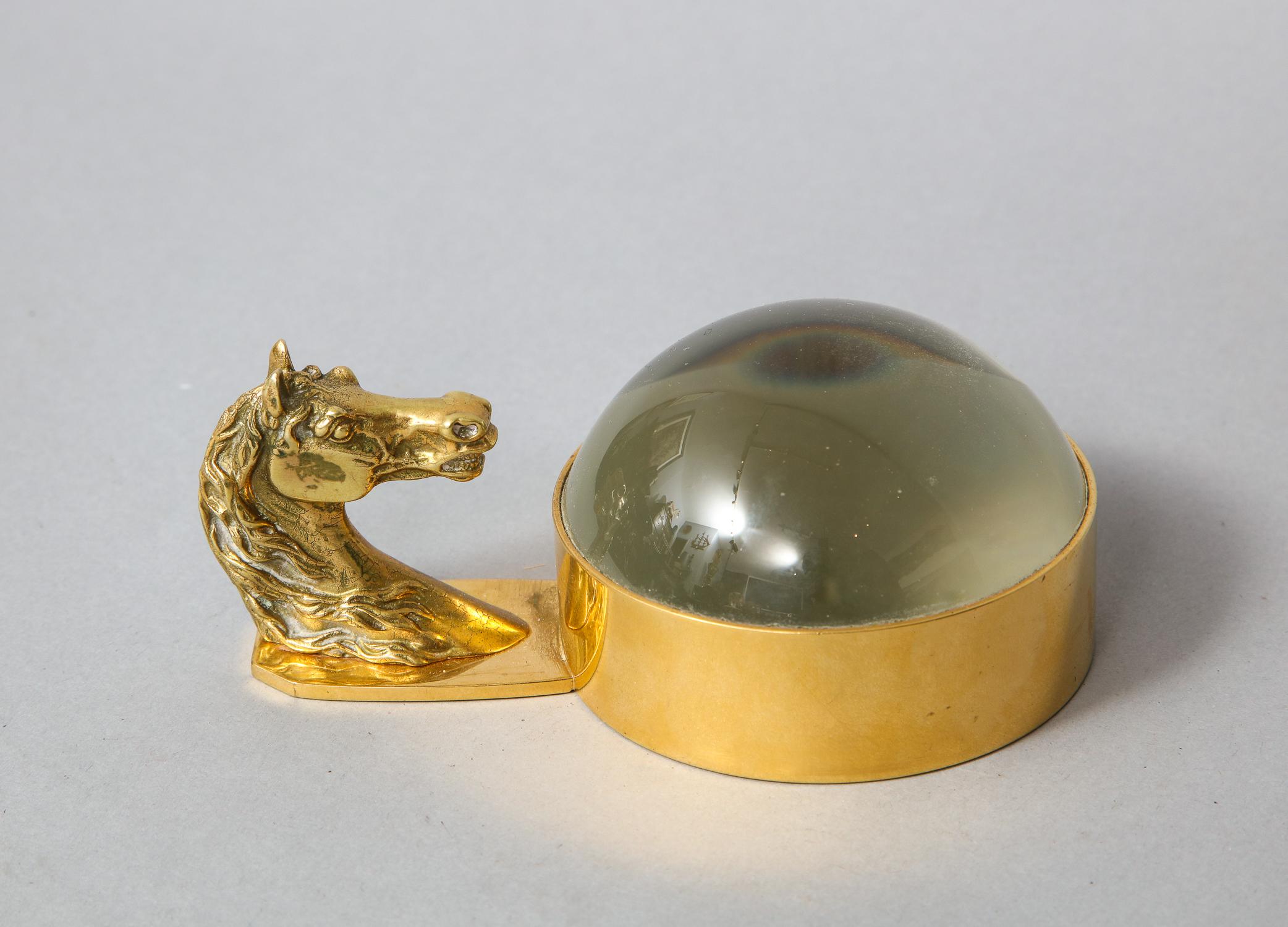 A paperweight with integral domed glass magnifier brass mounting ring and a horse's head handle, stamped Hermes, Paris, circa 1975.
