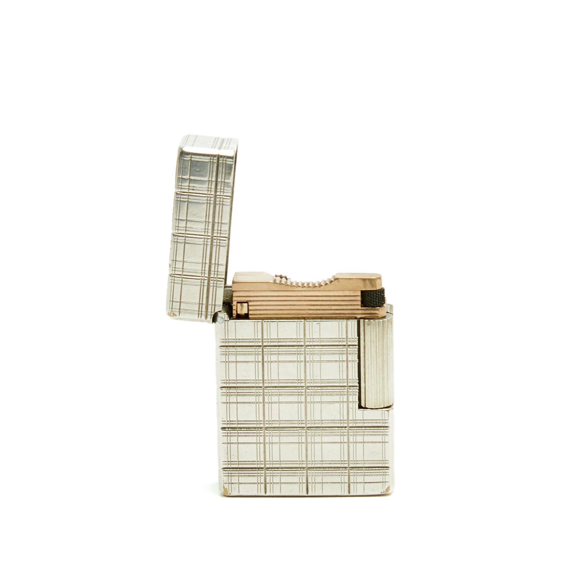 Accendino Hermès realizzato da ST Dupont, ricaricabile in argento massiccio con motivo tartan, revisionato da ST Dupont (11/2025) e consegnato in una (moderna) scatola di presentazione con marchio. Larghezza 3,5 cm x altezza 4,7 cm, peso 88,12 g.