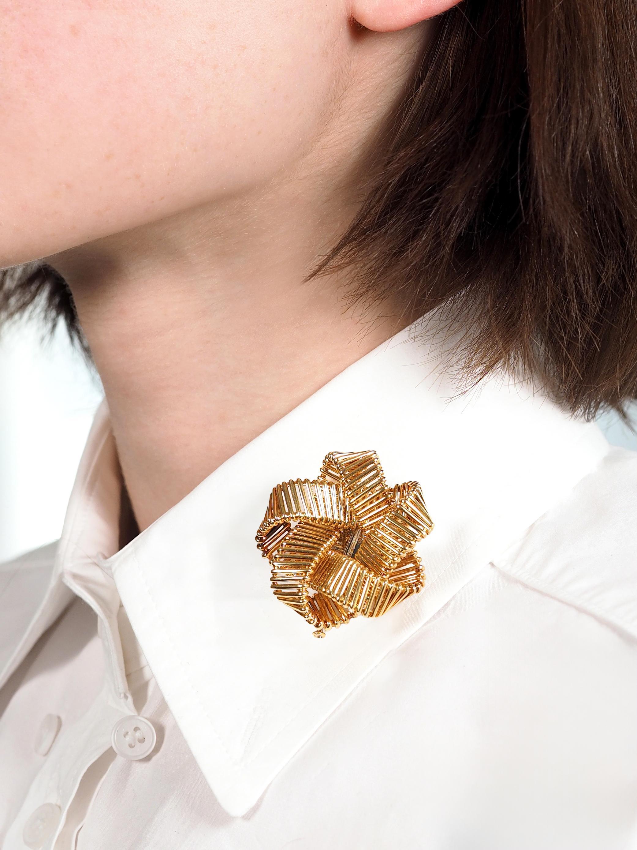 Diseñado como una forma de nudo dimensional en forma de estrella
Compuesto de alambre de oro formado como una cinta
Con un acabado muy pulido
Se completa con un pasador doble con bisagra y cierre de bloqueo
Estampado con sello francés de oro de 18