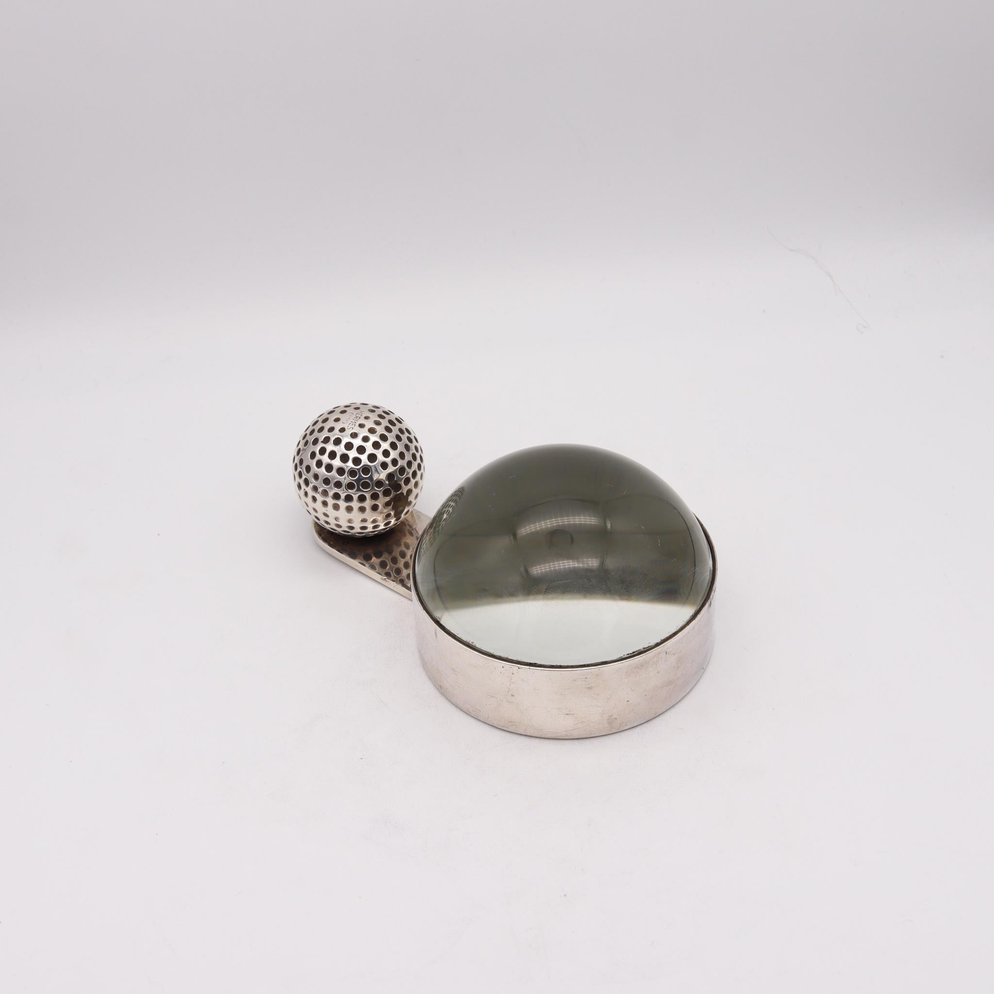 Desk magnifier glass designed by Hermes.

Fabulous and highly decorative piece, created in Paris, France by the house of Hermes, back in the 1960. This useful Golf Ball motif paper weight and magnifier glass is rare and has been carefully crafted