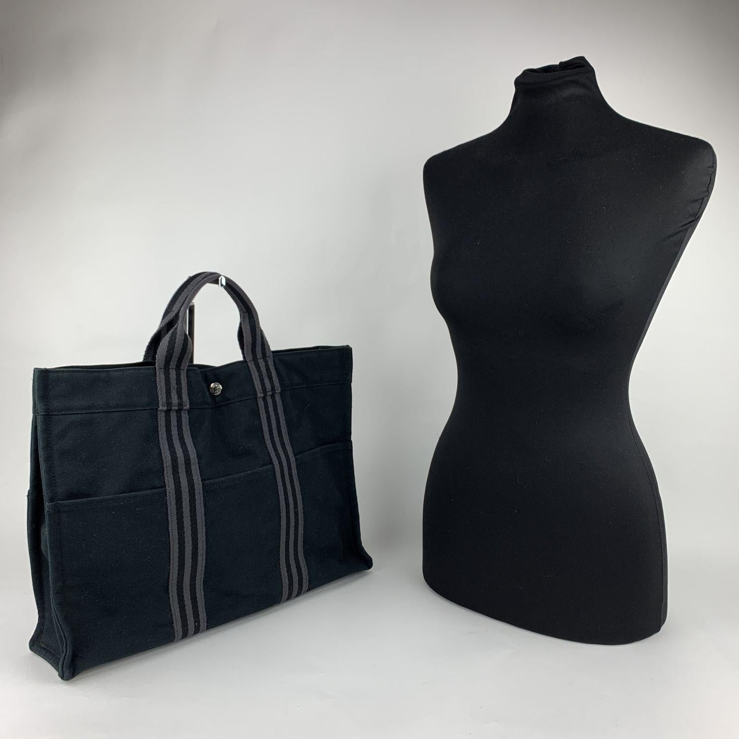 'HERMES FOURRE TOUT - MM' - Tote handbag. Made in France. Black color with grey stripes. Material: 100% cotton. It has snaps on both ends for expansion. Durable canvas handles, perfect for casual and everyday use. 3 open pockets on the front and 3