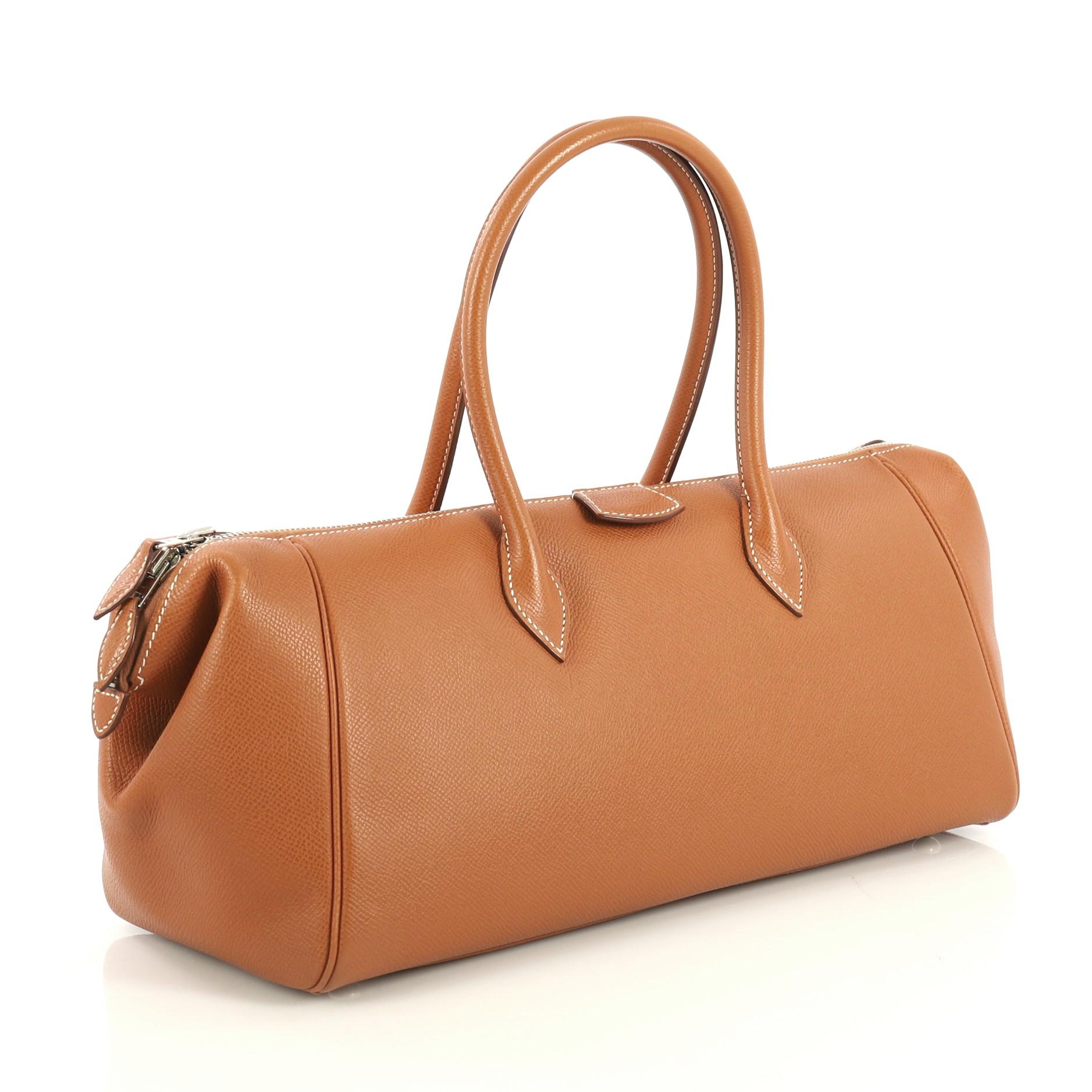 This Hermes Paris Bombay Satchel Epsom 35, crafted in Gold brown Epsom leather, features dual rolled handles and palladium hardware. Its zip closure opens to a Natural brown Agneau leather interior with slip pockets. Date stamp reads: K Square