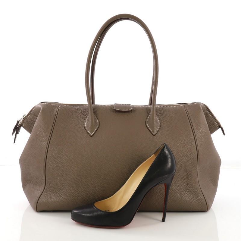 This Hermes Paris Bombay Satchel Togo 37, crated in Etoupe Togo leather, features dual rolled handles, protective base studs and palladium hardware. Its two-way top zip closure opens to a Natural beige Agneau leather interior with slip pockets. Date