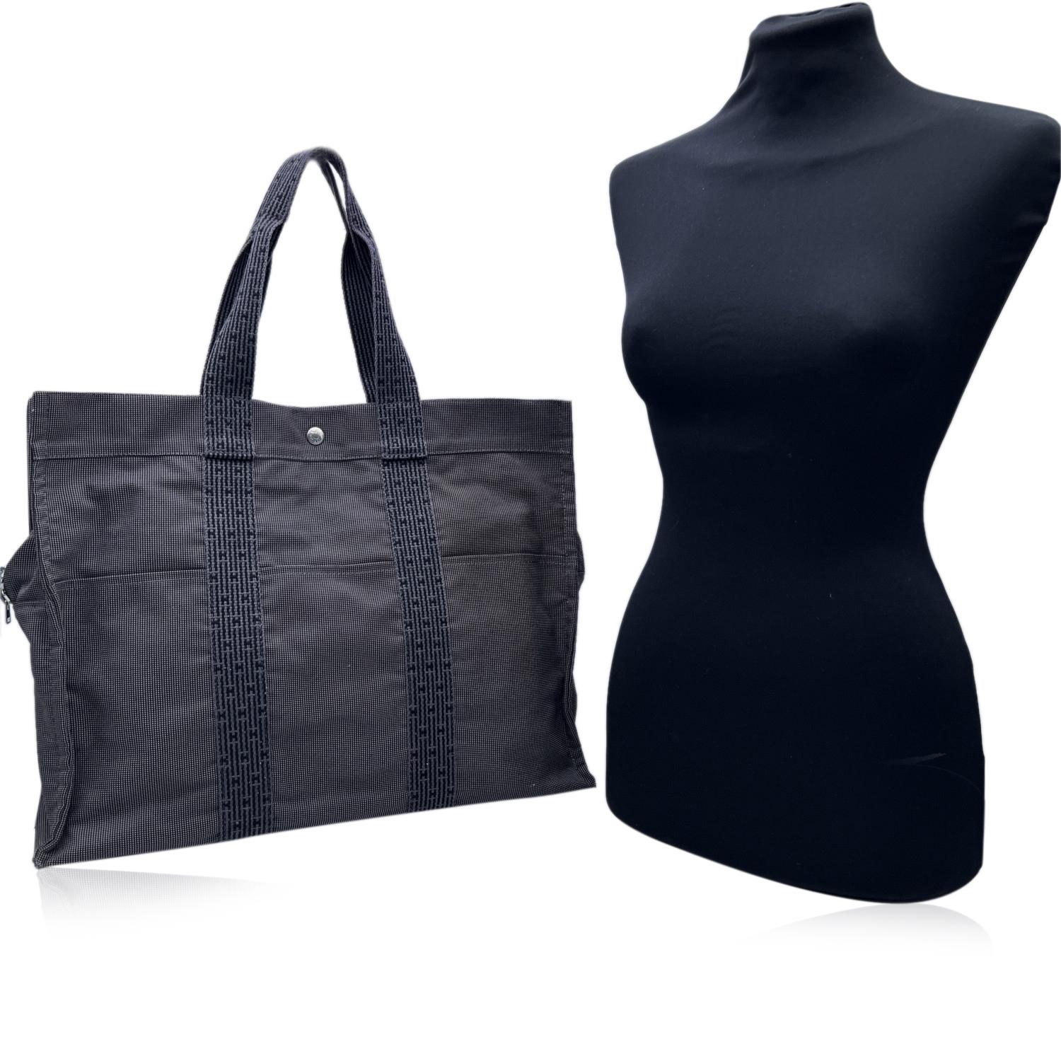 Hermes Canvas Herline Her Line GM Tote Bag in grey and black colors. Made of a durable canvas. The tote has durable strap handles of a patterned Hermes H canvas. 3 open pockets on the front. Composition; 69% Polyamide, 31% Polyester. 3 snap button