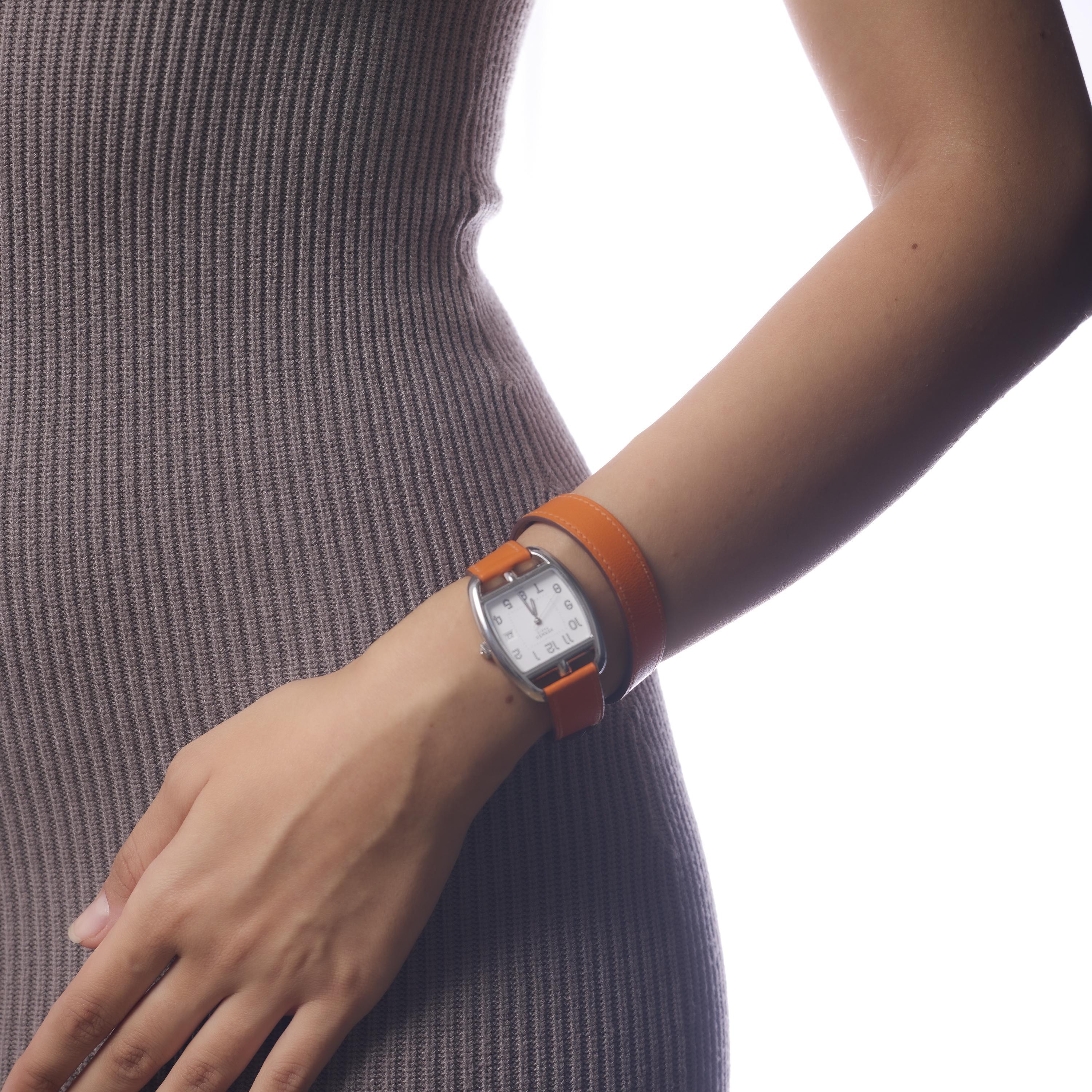 This contemporary Hermès Cape Cod Tonneau watch features a sleek stainless steel case paired with a supple calfskin leather strap. Elegant and understated, the 30mm x 33mm design is powered by a reliable quartz movement and hallmarked with Hermès