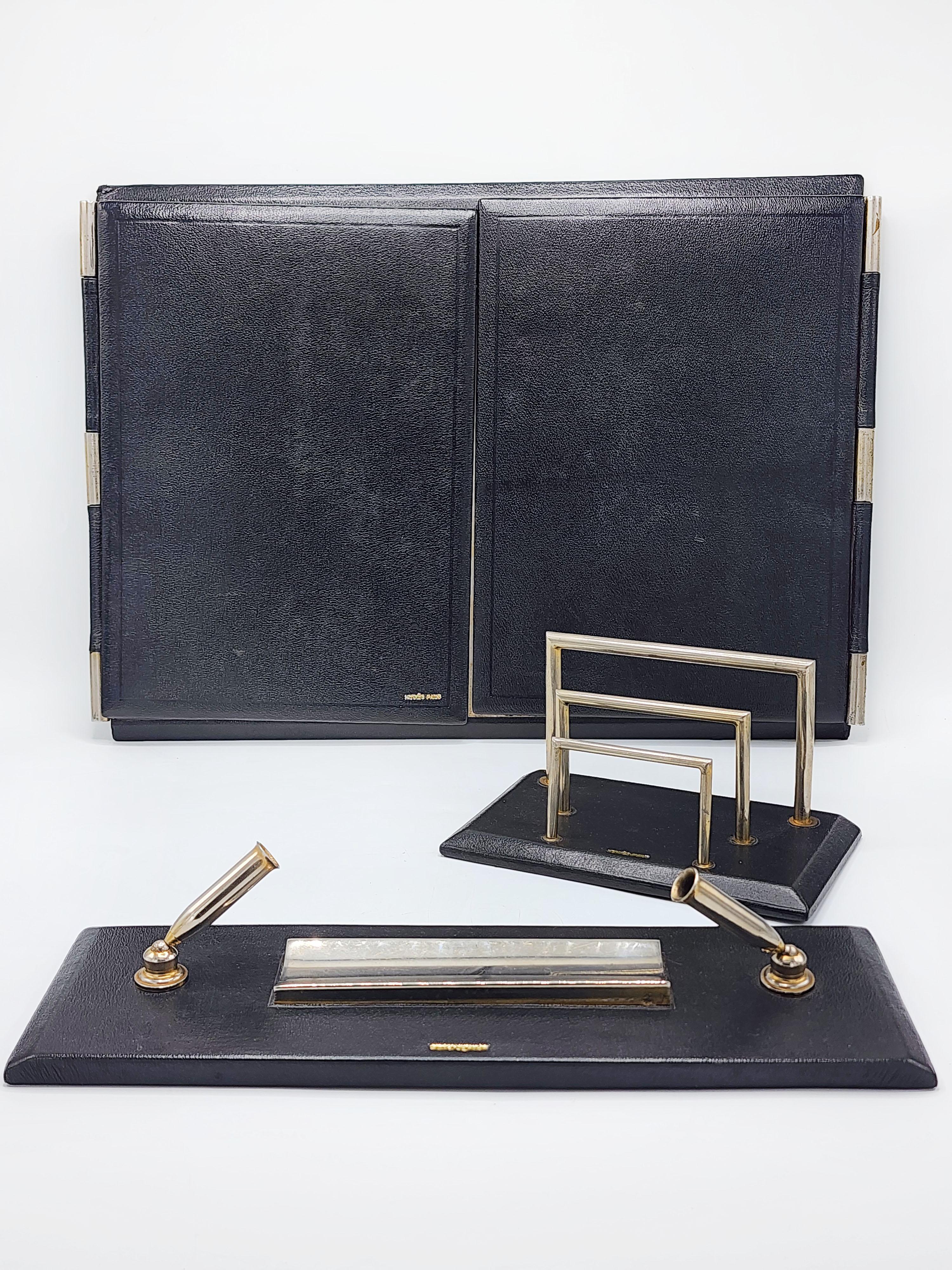 Schreibtischset von Hermes Paris aus schwarzem Leder und silbernem Metall
Schreibtischset, bestehend aus einem Schreibwarenhalter, einer Schreibtischmappe mit Doppelklappe und einem Stifthalter mit Löschblatt. Es ist ein Spiel, das Professionalität
