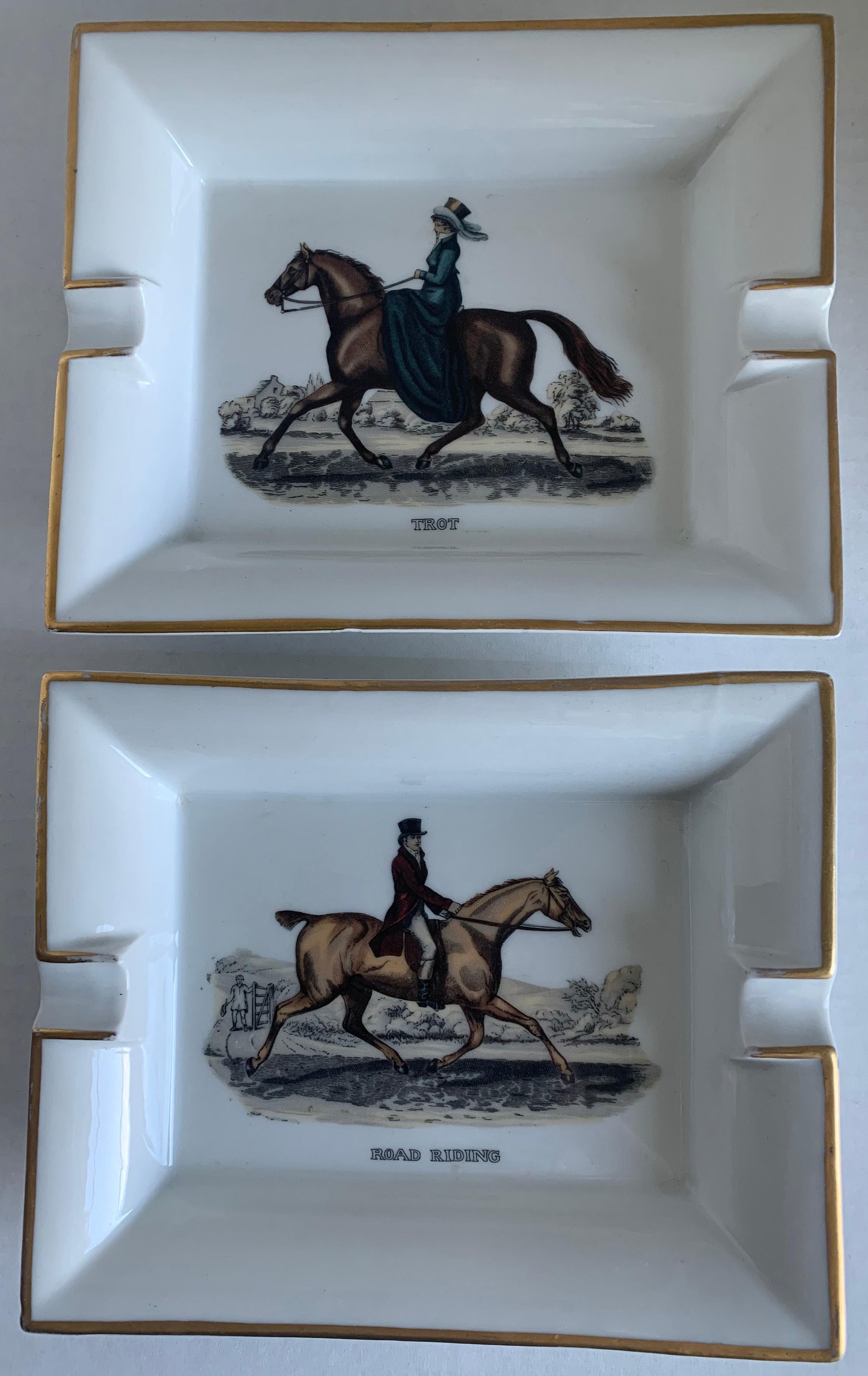 Pair of 1970s Hermès Paris porcelain equestrian ashtrays. Each ashtray features an equestrian motif with painted gold banding. Signed Hermès on the side of each ashtray.