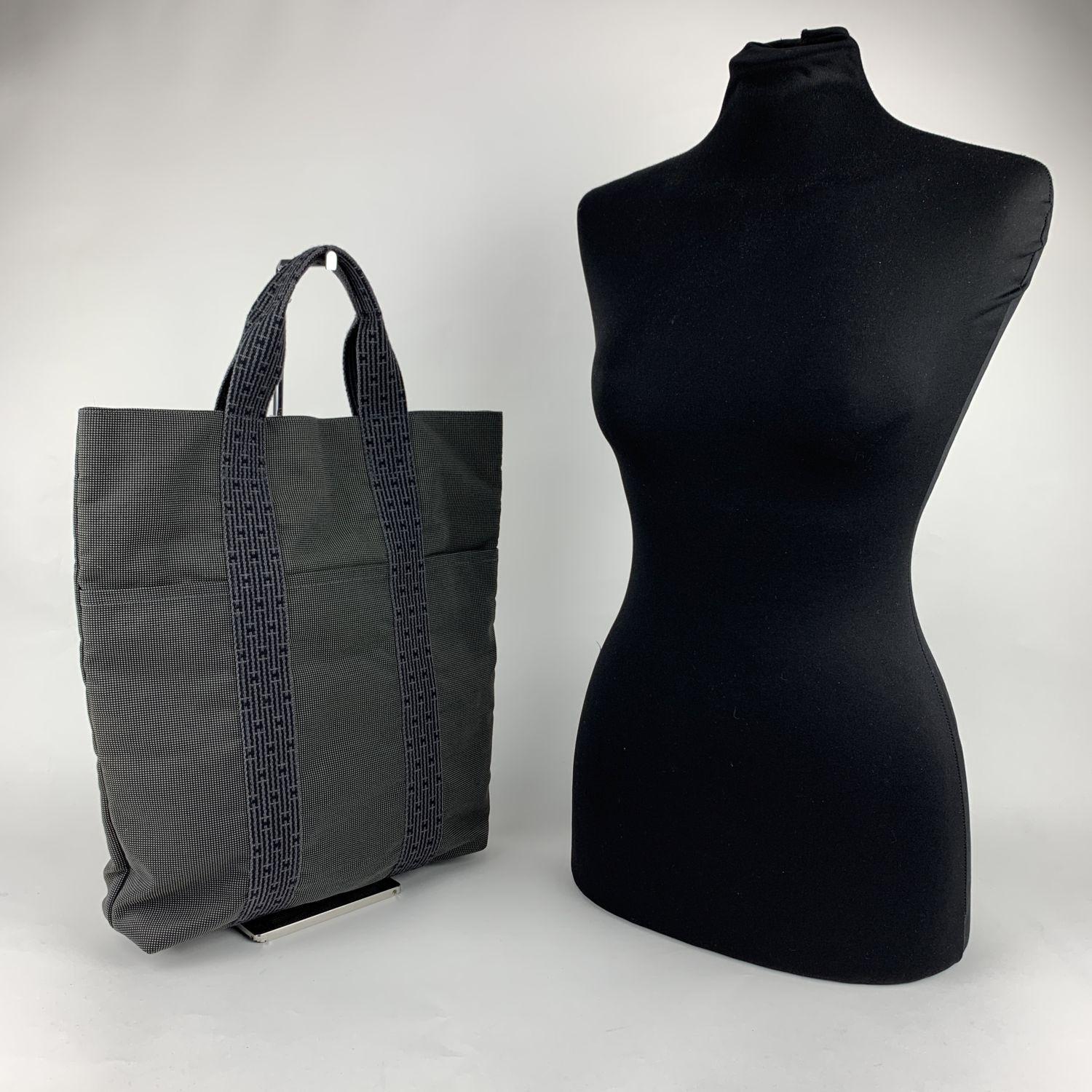 Hermes Grey Canvas Herline Her Line Shopping Bag. Made of a durable canvas. The tote has durable strap handles of a patterned Hermes H canvas. 3 open pockets on the front. Composition; 69% Polyamide, 31% Polyester. Upper zipper closure. Canvas