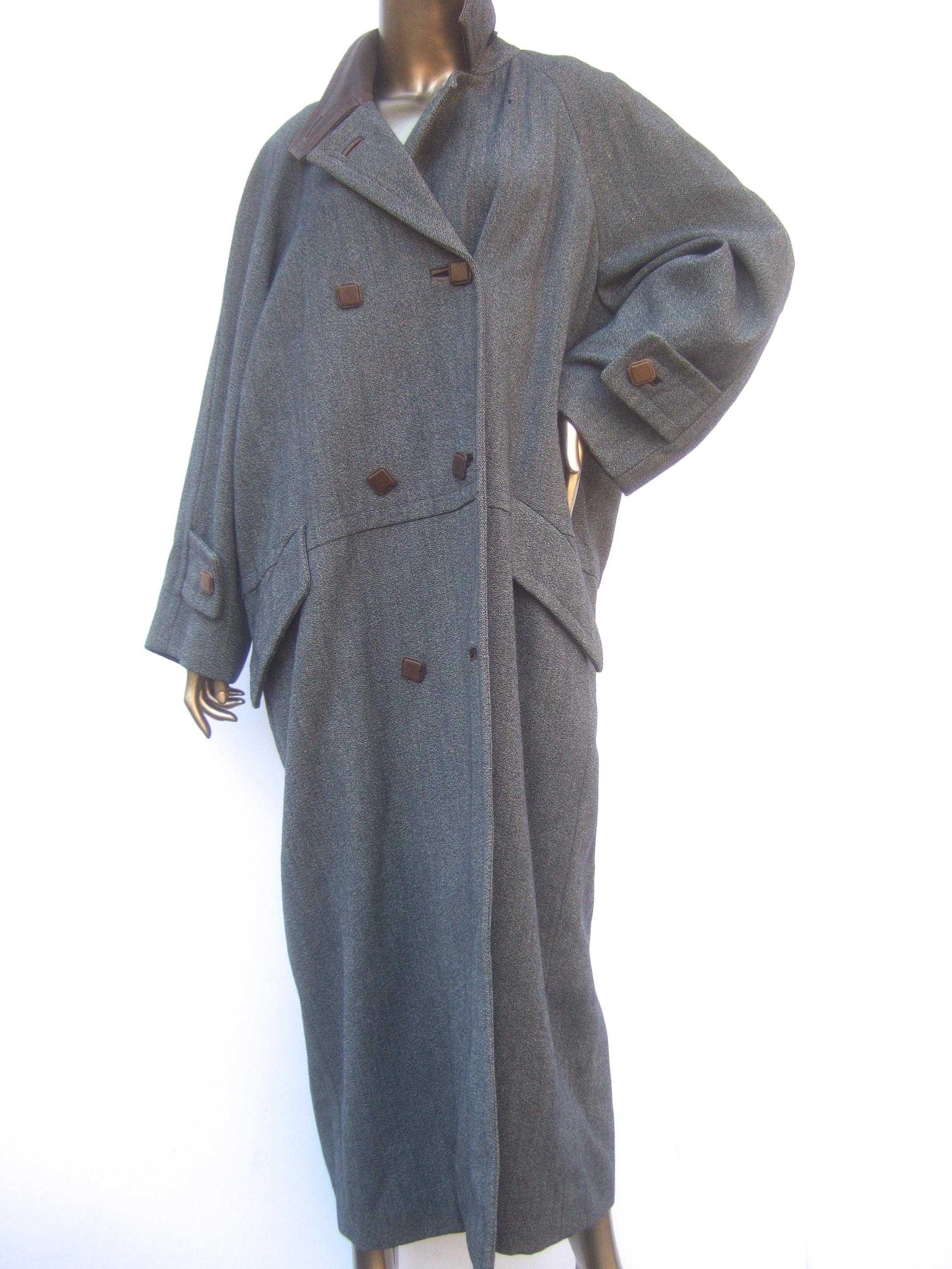 Hermes Paris Gray heavy gauge wool leather trim unisex winter coat c 1970s
The stylish vintage Hermes heavy wool coat is designed with a brown leather collar
Paired with brown leather square buttons that run down the front 

The coat is lined in