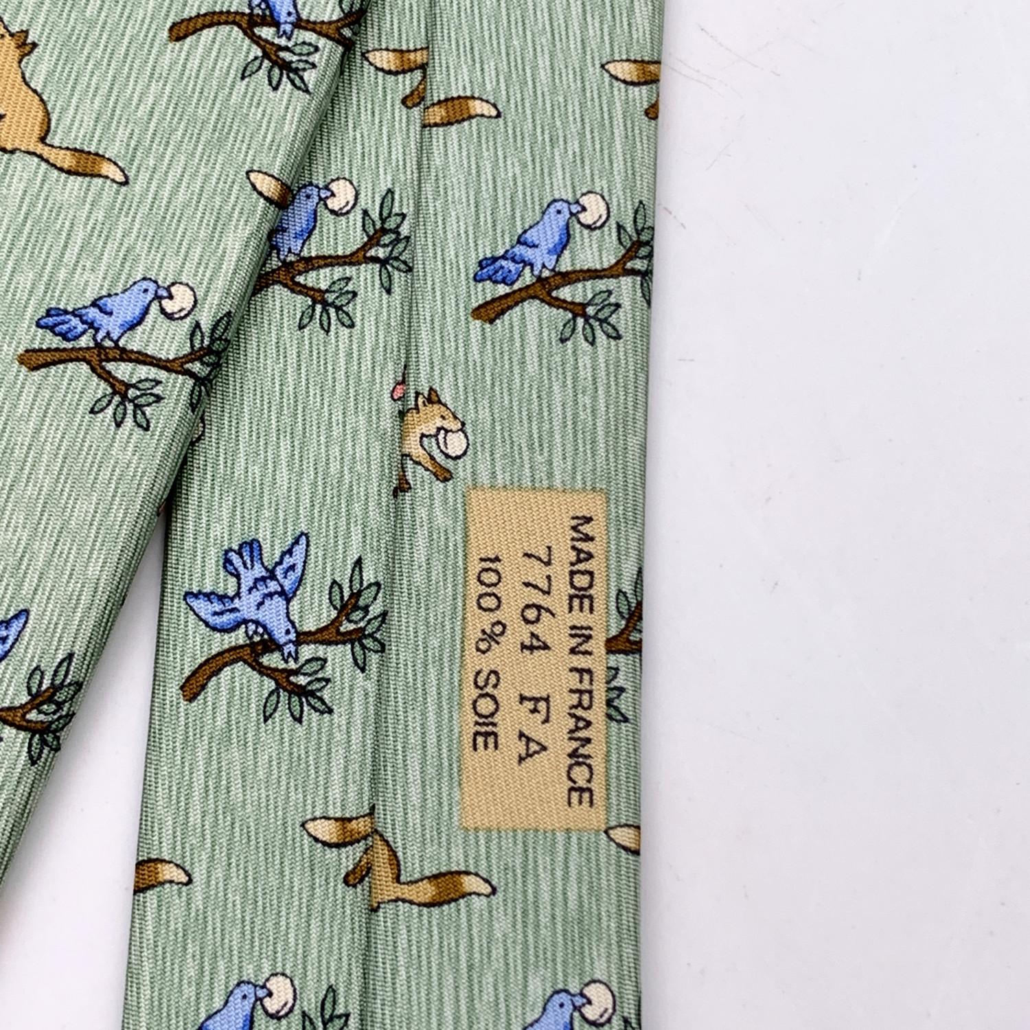 Elegant Hermes Neck Tie, 7764 FA, in light green color with 'The Fox and the Stork' fable print. Composition: 100% Silk. Hermes composition tag attached. 'HERMES Paris' with copyright symbol printed on the back. Made in France. Total length: 57