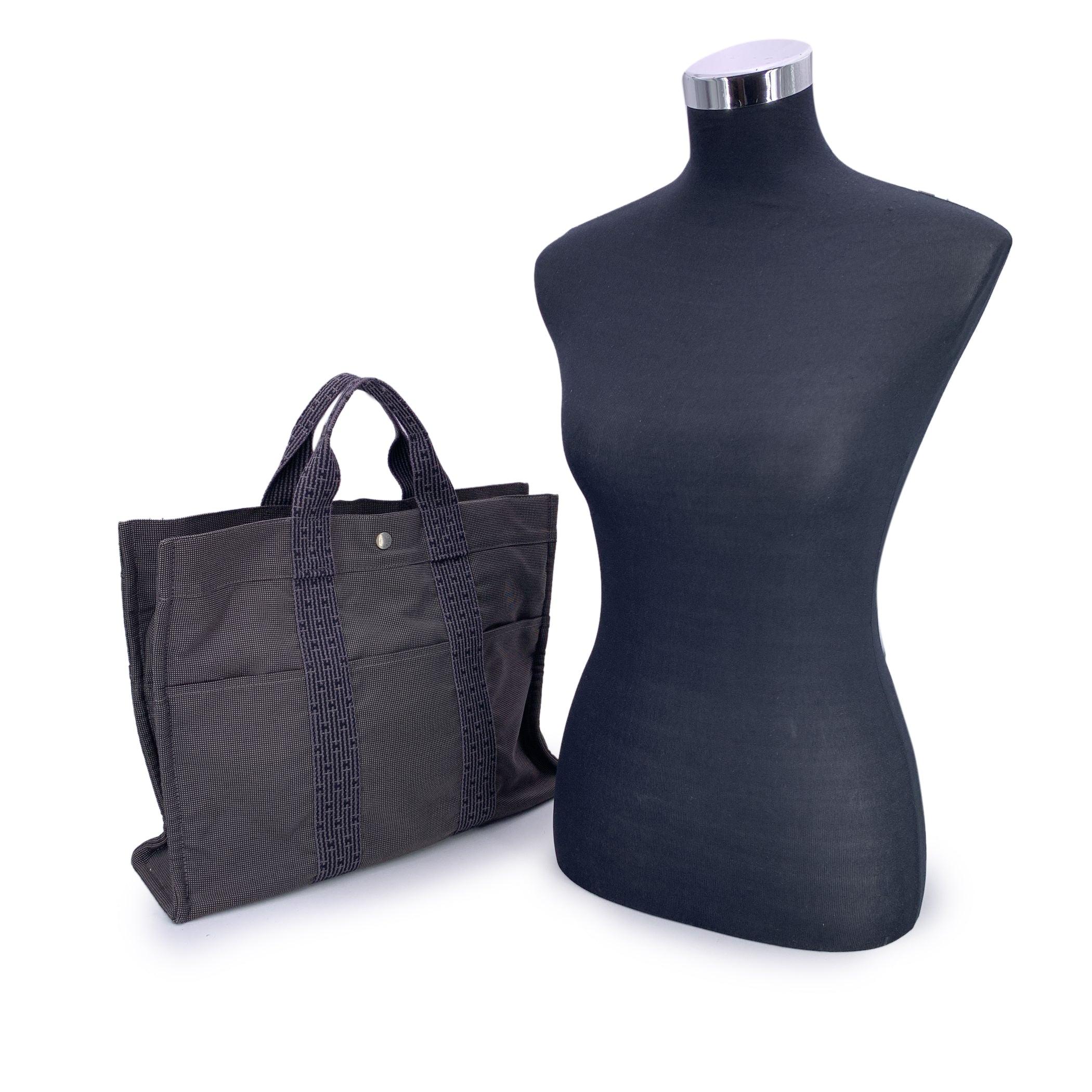 Hermes Canvas Herline Her Line Yale MM Tote Bag in grey and black colors. Made of a durable canvas. The tote has durable strap handles of a patterned Hermes H canvas. 3 open pockets on the front. Composition; 69% Polyamide, 31% Polyester. 3 snap
