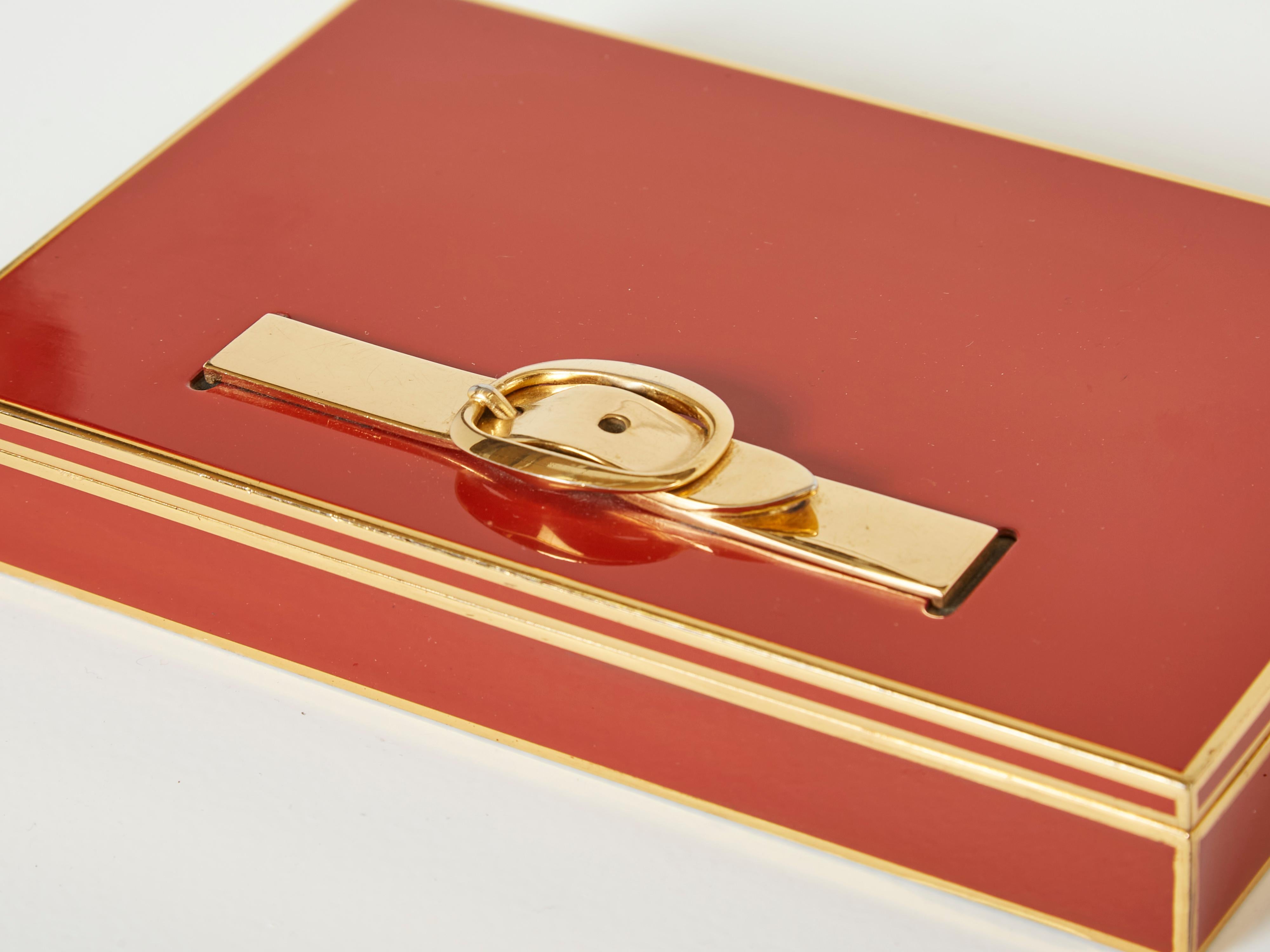 Beautiful French decorative box made by Hermès Paris in the 1970s. This red lacquered and brass jewellery box features a beautiful brass belt buckle on the top, with an interior covered with mahogany wood , with three compartments. The mix of red