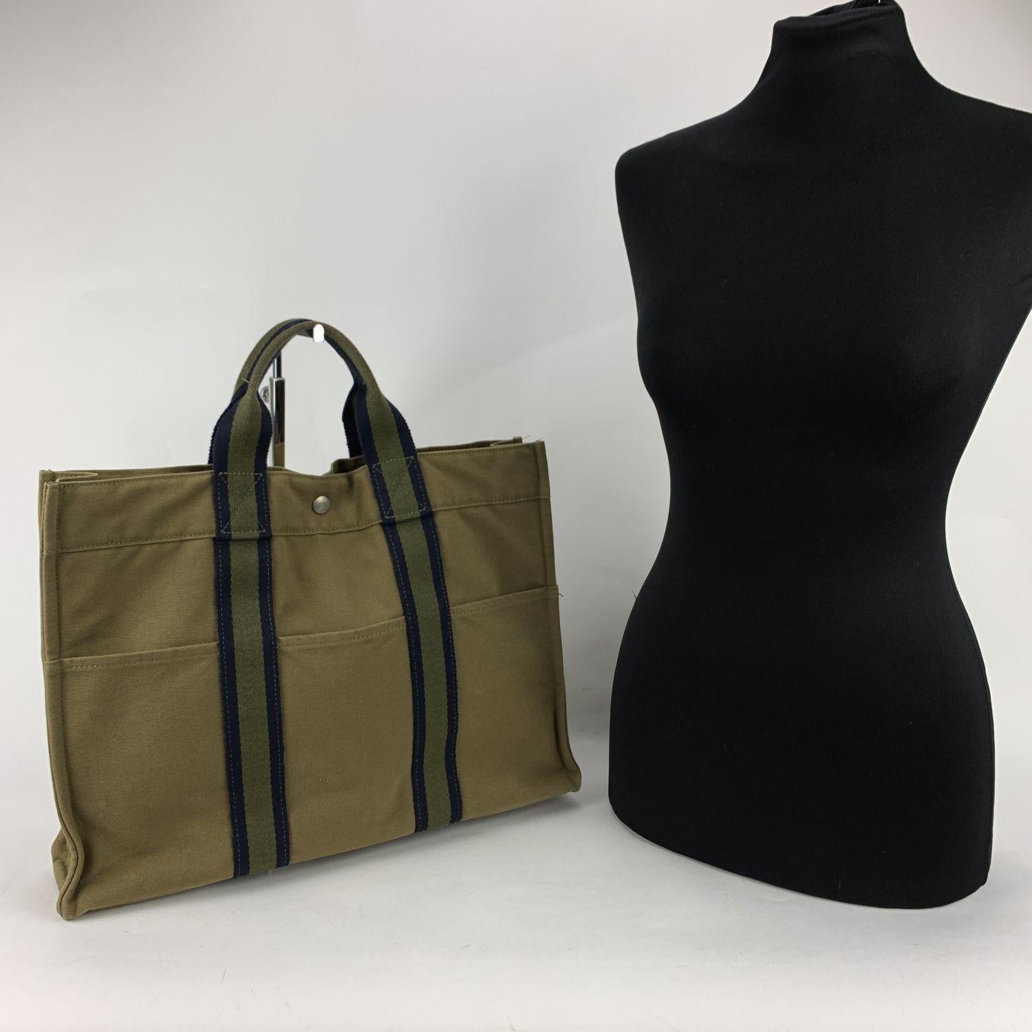 Hermes Paris Vintage green cotton canvas tote, Fourre Tout MM. Made in France. Blue stripes. 100% Cotton. 3 front pockets on the front and 3 pockets on the back. It has snaps (buttons) on both ends for expansion. Durable canvas handles, perfect for