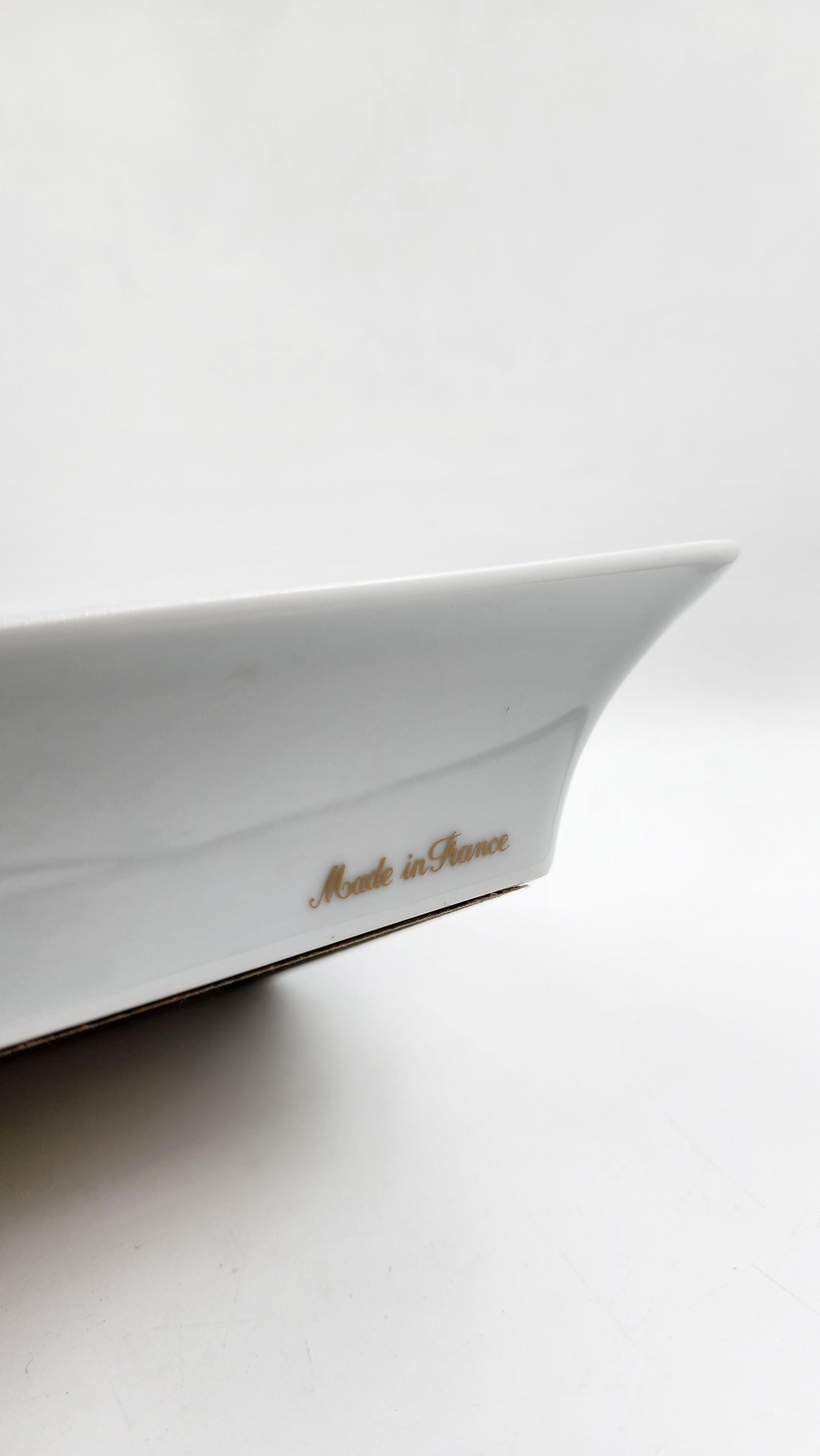 Hermes Paris Porcelain Ashtray
Rectangular white porcelain ashtray with gold details on the edges. It features a central design of a horse in harness and gold and black decoration. It has two side notches for resting