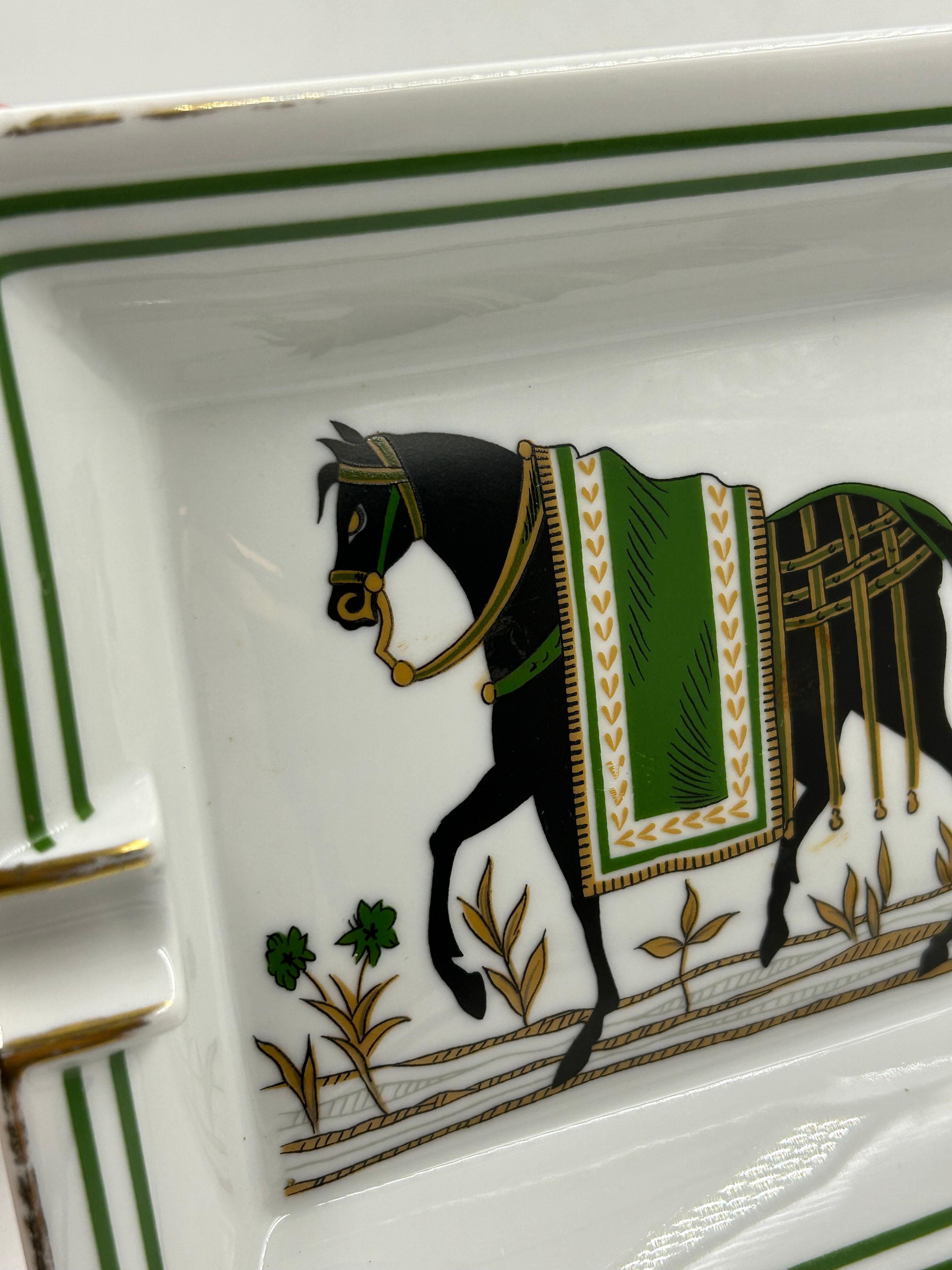 Hermès Paris Porcelain Ashtray
An elegant fine porcelain ashtray from Hermès Paris, decorated with a refined equestrian motif, one of the maison's most recognizable emblems. The piece features a black horse with an ornamental green blanket and