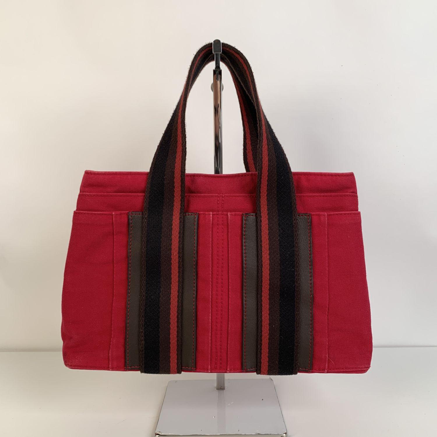 Hermès Horizontal Troca PM bag crafted in a red cotton canvas with genuine leather trim. It features double top handles, 4 front slip pockets and upper button closure. Canvas lining and and 1 zip pocket inside. 'Hermes' tag