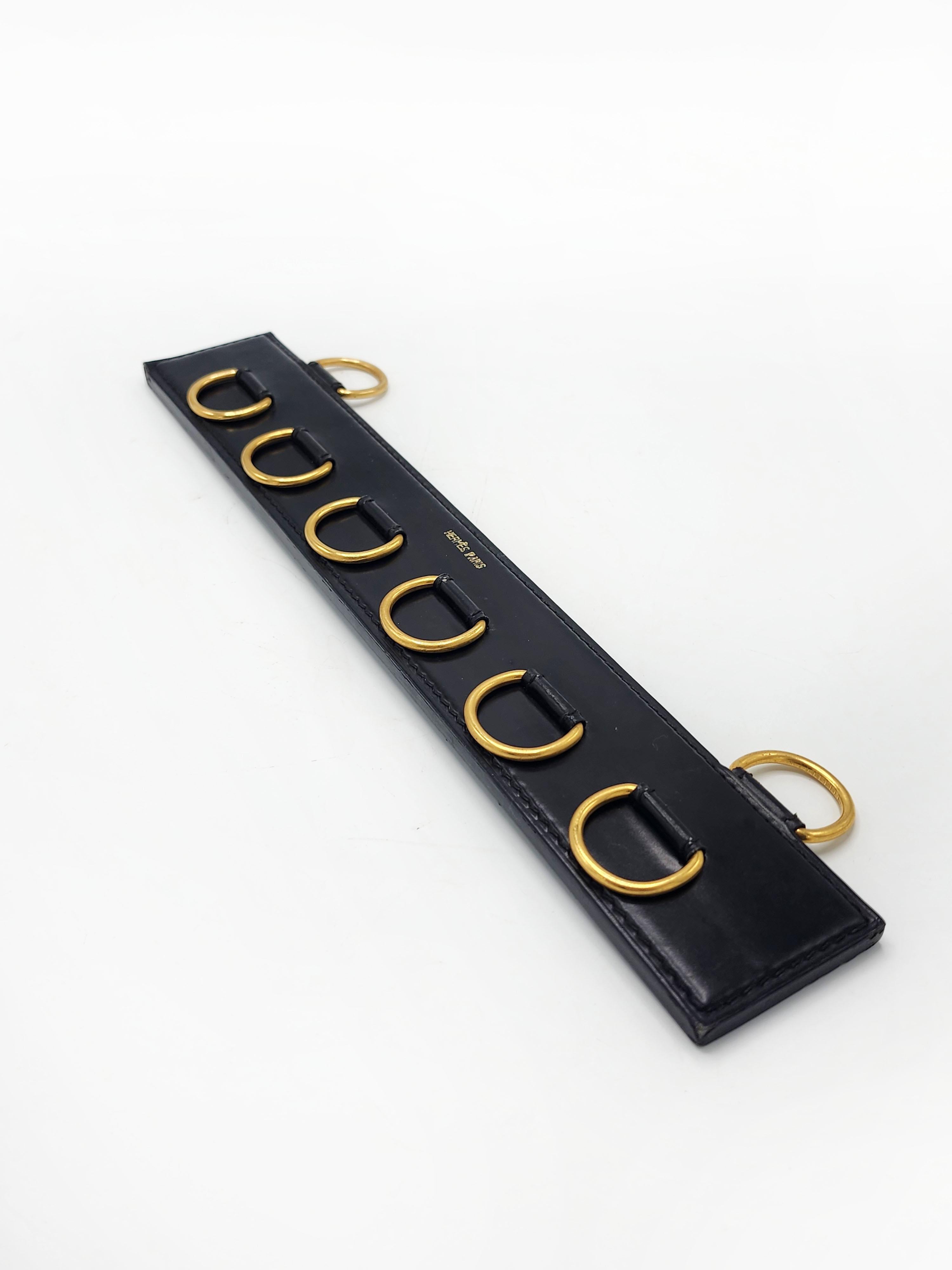 Hermes Paris Scarf Hanger
A scarf hanger with rings attached to a genuine leather board. There are 6 scarf hanging rings and 2 wall hanging rings. It has a simple design in which only the metal hardware and seams stand out, reminiscent of horse