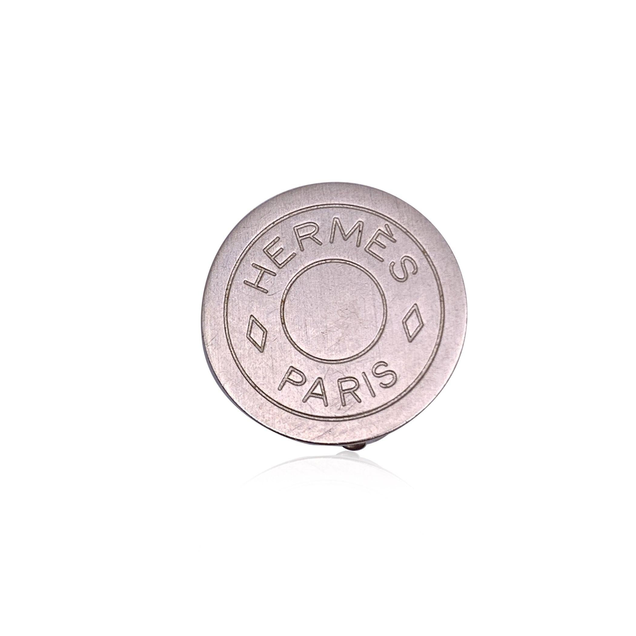 Discover the understated elegance of these vintage Hermes silver metal round 'Clou de Selle' clip-on earrings. With a sleek and minimalist design, these 20mm diameter earrings feature the iconic Clou de Selle motif, a symbol of the house's