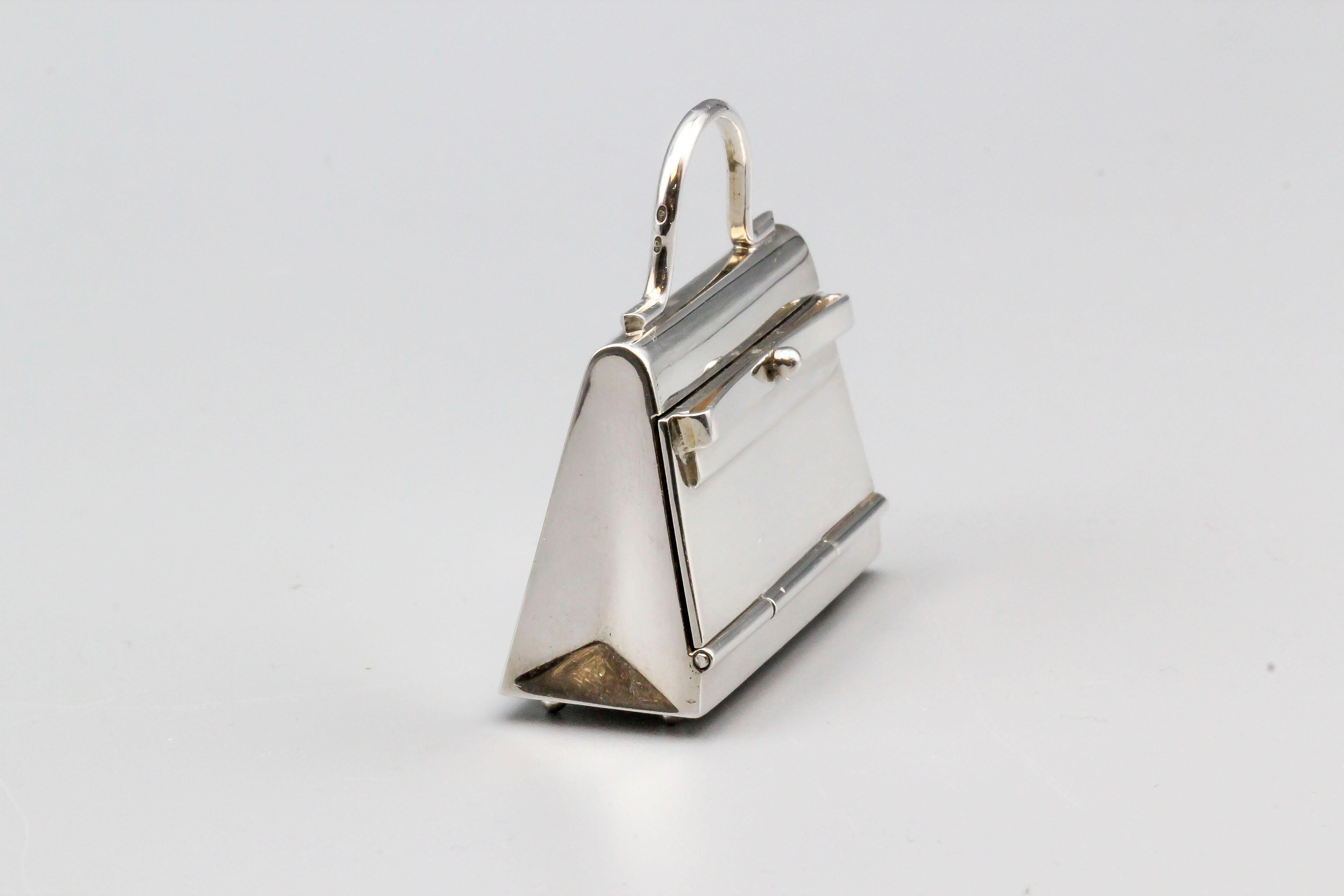 Fine sterling silver pill box in the likeness of an Hermes Kelly bag, by Hermes.  The box can be used in a multitude of ways: as a standard pillbox, a pendant, or as a charm.  Almost 2 inches wide and approx. 40 grams in weight.

Hallmarks: Hermes