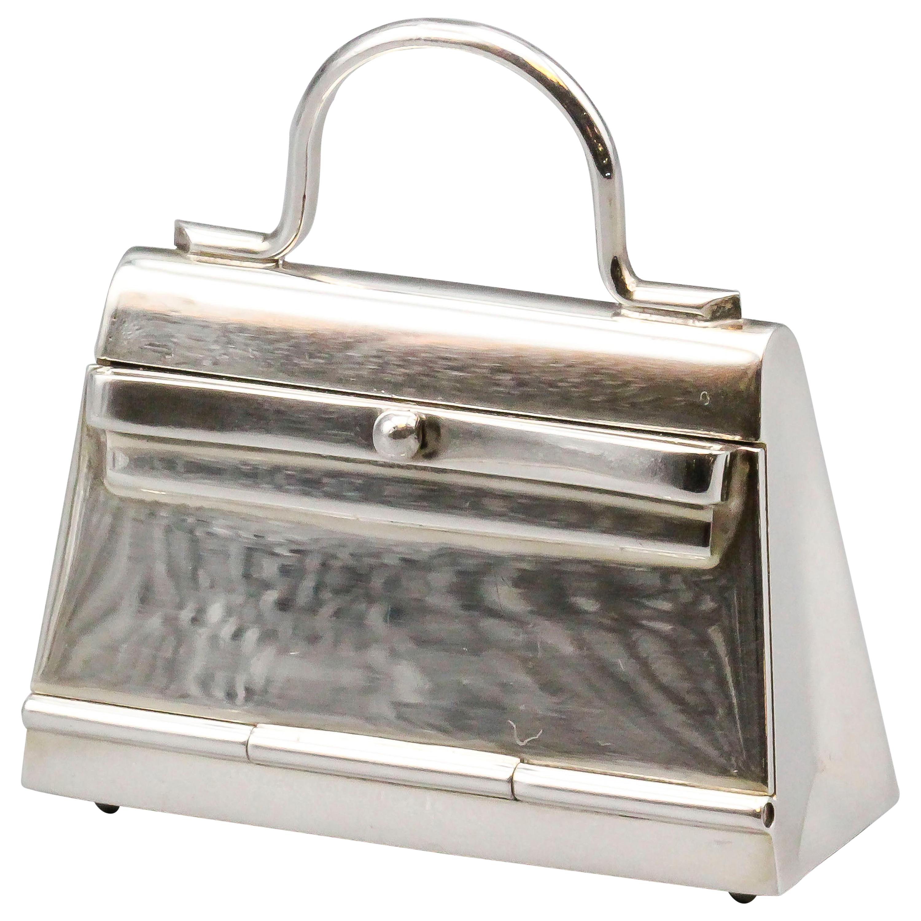 Fine sterling silver pill box in the likeness of an Hermes Kelly bag, by Hermes circa 1980s.  The box can be used in a multitude of ways: as a standard pillbox, a pendant, or as a charm.  Approx. 1.75 inches wide and approx. 40 grams in