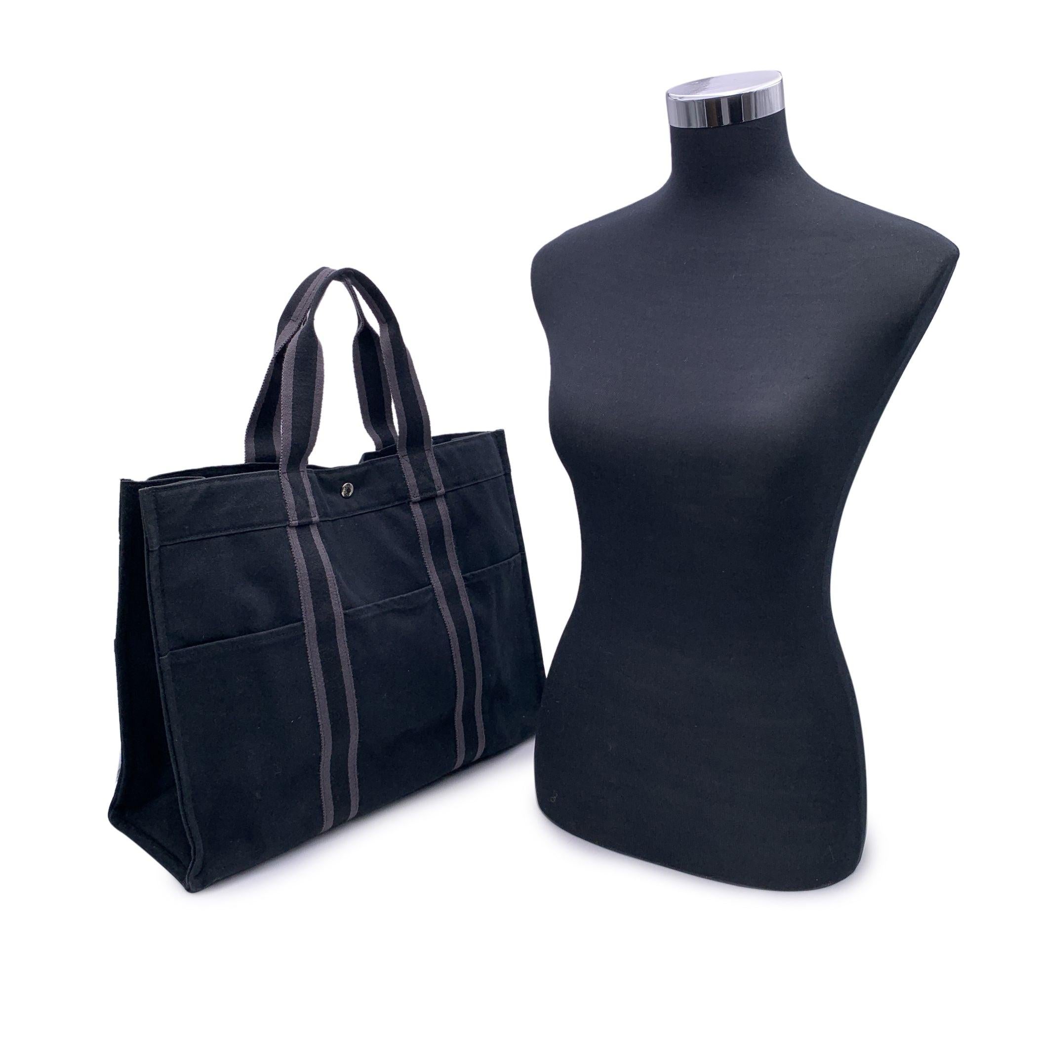 HERMES FOURRE TOUT - GM' - Tote handbag. Made in France. Black color with grey stripes. Material: 100% cotton. It has snaps on both ends for expansion. Durable canvas handles, perfect for casual and everyday use. 3 open pockets on the front and 3